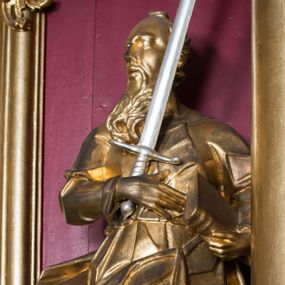 Zdjęcie nr 1: Rzeźba ścięta z tyłu i drążona, ustawiona na niskiej podstawie. 
Święty zwrócony w trzech czwartych w prawo, w kontrapoście. Lewą ręką przyciska do boku księgę, prawą kładzie na piersi i przytrzymuje miecz skierowany ostrzem w górę. Twarz ma pociągłą z wysokim czołem, o okrągłych, wyłupiastych oczach, garbatym nosie i pełnych, rozchylonych ustach; okoloną długą, rozdwajającą się brodą, opadającą na pierś oraz krótkimi, kręconymi włosami. Święty ubrany jest w tunikę ściśle przylegającą do ciała, przepasaną w talii, ostro łamaną oraz płaszcz wywinięty na prawym boku postaci, podwieszony nad lewym udem. Figura w całości złocona, miecz srebrzony. 