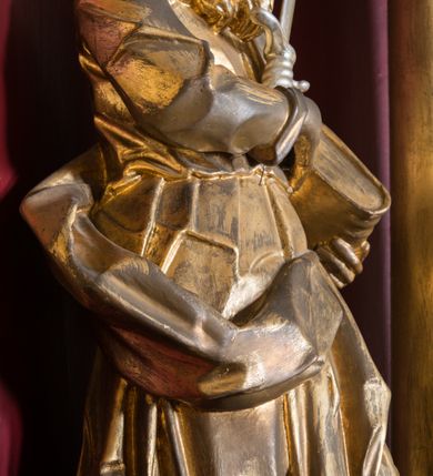 Zdjęcie nr 3: Rzeźba ścięta z tyłu i drążona, ustawiona na niskiej podstawie. 
Święty zwrócony w trzech czwartych w prawo, w kontrapoście. Lewą ręką przyciska do boku księgę, prawą kładzie na piersi i przytrzymuje miecz skierowany ostrzem w górę. Twarz ma pociągłą z wysokim czołem, o okrągłych, wyłupiastych oczach, garbatym nosie i pełnych, rozchylonych ustach; okoloną długą, rozdwajającą się brodą, opadającą na pierś oraz krótkimi, kręconymi włosami. Święty ubrany jest w tunikę ściśle przylegającą do ciała, przepasaną w talii, ostro łamaną oraz płaszcz wywinięty na prawym boku postaci, podwieszony nad lewym udem. Figura w całości złocona, miecz srebrzony. 