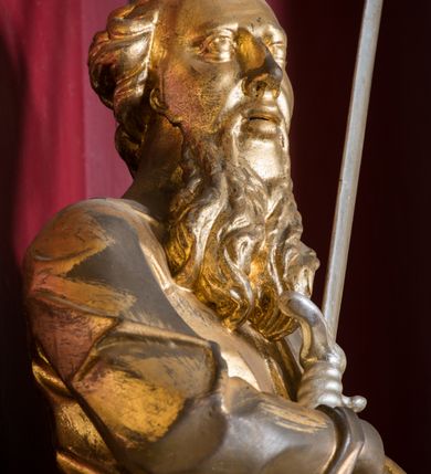 Zdjęcie nr 14: Rzeźba ścięta z tyłu i drążona, ustawiona na niskiej podstawie. 
Święty zwrócony w trzech czwartych w prawo, w kontrapoście. Lewą ręką przyciska do boku księgę, prawą kładzie na piersi i przytrzymuje miecz skierowany ostrzem w górę. Twarz ma pociągłą z wysokim czołem, o okrągłych, wyłupiastych oczach, garbatym nosie i pełnych, rozchylonych ustach; okoloną długą, rozdwajającą się brodą, opadającą na pierś oraz krótkimi, kręconymi włosami. Święty ubrany jest w tunikę ściśle przylegającą do ciała, przepasaną w talii, ostro łamaną oraz płaszcz wywinięty na prawym boku postaci, podwieszony nad lewym udem. Figura w całości złocona, miecz srebrzony. 