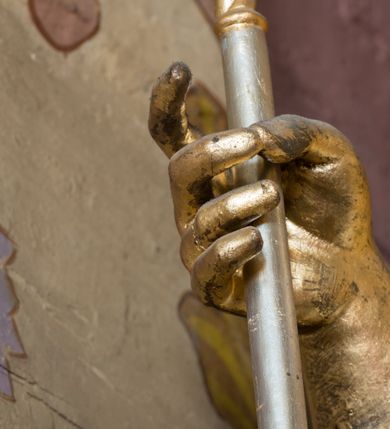 Zdjęcie nr 11: Rzeźba ścięta z tyłu i drążona, ustawiona na niskiej podstawie. Święty zwrócony w trzech czwartych w lewo, z pochyloną głową, w kontrapoście i lekko esowato wygiętą sylwetką. W prawej, wysuniętej w bok ręce trzyma pastorał, lewą podtrzymuje otwartą księgę, na której leżą trzy kule. Twarz ma szczupłą, pociągłą, o podkreślonych kościach policzkowych, blisko osadzonych, migdałowatych oczach, dużym nosie i wąskich ustach. Twarz okolona jest gęstą brodą opadającą na pierś, rzeźbioną w drobne pukle oraz półdługimi, kręconymi włosami opadającymi w na tył głowy. Na głowie ma infułę z taśmami (fannones). Święty ubrany jest w albę, rokietę dekorowaną przy brzegu płaskorzeźbioną koronką, mucet, stułę, kapę zapiętą na piersi, na dłoniach ma rękawiczki. Przy lewej nodze szaflik z trzema półpostaciami w środku z głowami skierowanymi w górę i rękami złożonymi w geście modlitwy. Figura niemal w całości złocona, detale stroju srebrzone, szaflik polichromowany na czerwono. 