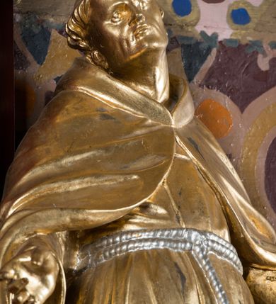 Zdjęcie nr 16: Nastawa architektoniczna, jednoosiowa, jednokondygnacyjna ze zwieńczeniem, na wysokim cokole z wyodrębnionymi konsolami. Ołtarz drewniany, sarkofagowy, na cokole, zwężający się ku dołowi z drewnianą mensą i kamiennym portatylem. Na mensie ustawione tabernakulum w formie prostopadłościennej skrzynki. Ścianka frontowa ujęta ornamentalnymi listewkami; drzwiczki w kształcie stojącego prostokąta w ornamentalnej ramie z płaskorzeźbionym przedstawieniem kielicha z hostią i winnym gronem. Nastawa ujęta parą zdwojonych pilastrów zwróconych pod kątem na zewnątrz, dekorowanych zwisami kwiatowymi, dźwigających silnie wysunięte imposty podtrzymywane przez konsole. Na tle pilastrów figury św. Antoniego Padewskiego i św. Franciszka ustawione na konsolach. W polu środkowym obraz św. Franciszka w formie stojącego prostokąta ujęty profilowaną ramą zdobioną rocaille'em. Powyżej wolutowe fragmenty rocaille'u, pod nim płycina. Zwieńczenie w formie trapezu ujętego spływami wolutowymi, dekorowanymi liśćmi palmowymi, ze ślimacznicami w kształcie meandru, spływającymi na belkowanie, na których stoją wazony. Całość zamknięta fragmentem wyłamanego trójbocznie gzymsu, zwieńczonego rokokowym szczytem z kwiatowymi gałązkami. W polu obraz św. Franciszki Rzymskiej w formie zbliżonej do zwieńczenia, ujęty ramą dekorowaną rocaille'em. Struktura polichromowana w kolorze głębokiej czerwieni, z czarnymi profilami oraz złoconymi ramami, profilami i ornamentyką.
