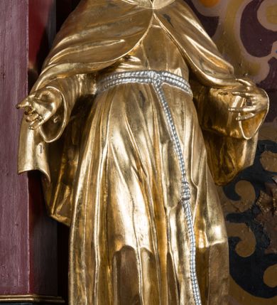 Zdjęcie nr 19: Nastawa architektoniczna, jednoosiowa, jednokondygnacyjna ze zwieńczeniem, na wysokim cokole z wyodrębnionymi konsolami. Ołtarz drewniany, sarkofagowy, na cokole, zwężający się ku dołowi z drewnianą mensą i kamiennym portatylem. Na mensie ustawione tabernakulum w formie prostopadłościennej skrzynki. Ścianka frontowa ujęta ornamentalnymi listewkami; drzwiczki w kształcie stojącego prostokąta w ornamentalnej ramie z płaskorzeźbionym przedstawieniem kielicha z hostią i winnym gronem. Nastawa ujęta parą zdwojonych pilastrów zwróconych pod kątem na zewnątrz, dekorowanych zwisami kwiatowymi, dźwigających silnie wysunięte imposty podtrzymywane przez konsole. Na tle pilastrów figury św. Antoniego Padewskiego i św. Franciszka ustawione na konsolach. W polu środkowym obraz św. Franciszka w formie stojącego prostokąta ujęty profilowaną ramą zdobioną rocaille'em. Powyżej wolutowe fragmenty rocaille'u, pod nim płycina. Zwieńczenie w formie trapezu ujętego spływami wolutowymi, dekorowanymi liśćmi palmowymi, ze ślimacznicami w kształcie meandru, spływającymi na belkowanie, na których stoją wazony. Całość zamknięta fragmentem wyłamanego trójbocznie gzymsu, zwieńczonego rokokowym szczytem z kwiatowymi gałązkami. W polu obraz św. Franciszki Rzymskiej w formie zbliżonej do zwieńczenia, ujęty ramą dekorowaną rocaille'em. Struktura polichromowana w kolorze głębokiej czerwieni, z czarnymi profilami oraz złoconymi ramami, profilami i ornamentyką.
