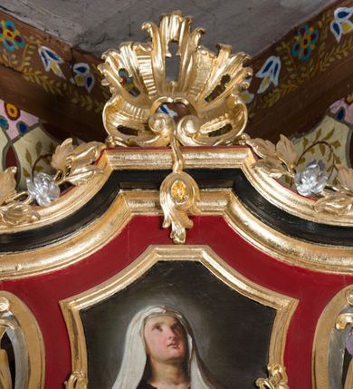 Zdjęcie nr 53: Nastawa architektoniczna, jednoosiowa, jednokondygnacyjna ze zwieńczeniem, na wysokim cokole z wyodrębnionymi konsolami. Ołtarz drewniany, sarkofagowy, na cokole, zwężający się ku dołowi z drewnianą mensą i kamiennym portatylem. Na mensie ustawione tabernakulum w formie prostopadłościennej skrzynki. Ścianka frontowa ujęta ornamentalnymi listewkami; drzwiczki w kształcie stojącego prostokąta w ornamentalnej ramie z płaskorzeźbionym przedstawieniem kielicha z hostią i winnym gronem. Nastawa ujęta parą zdwojonych pilastrów zwróconych pod kątem na zewnątrz, dekorowanych zwisami kwiatowymi, dźwigających silnie wysunięte imposty podtrzymywane przez konsole. Na tle pilastrów figury św. Antoniego Padewskiego i św. Franciszka ustawione na konsolach. W polu środkowym obraz św. Franciszka w formie stojącego prostokąta ujęty profilowaną ramą zdobioną rocaille'em. Powyżej wolutowe fragmenty rocaille'u, pod nim płycina. Zwieńczenie w formie trapezu ujętego spływami wolutowymi, dekorowanymi liśćmi palmowymi, ze ślimacznicami w kształcie meandru, spływającymi na belkowanie, na których stoją wazony. Całość zamknięta fragmentem wyłamanego trójbocznie gzymsu, zwieńczonego rokokowym szczytem z kwiatowymi gałązkami. W polu obraz św. Franciszki Rzymskiej w formie zbliżonej do zwieńczenia, ujęty ramą dekorowaną rocaille'em. Struktura polichromowana w kolorze głębokiej czerwieni, z czarnymi profilami oraz złoconymi ramami, profilami i ornamentyką.
