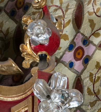 Zdjęcie nr 58: Nastawa architektoniczna, jednoosiowa, jednokondygnacyjna ze zwieńczeniem, na wysokim cokole z wyodrębnionymi konsolami. Ołtarz drewniany, sarkofagowy, na cokole, zwężający się ku dołowi z drewnianą mensą i kamiennym portatylem. Na mensie ustawione tabernakulum w formie prostopadłościennej skrzynki. Ścianka frontowa ujęta ornamentalnymi listewkami; drzwiczki w kształcie stojącego prostokąta w ornamentalnej ramie z płaskorzeźbionym przedstawieniem kielicha z hostią i winnym gronem. Nastawa ujęta parą zdwojonych pilastrów zwróconych pod kątem na zewnątrz, dekorowanych zwisami kwiatowymi, dźwigających silnie wysunięte imposty podtrzymywane przez konsole. Na tle pilastrów figury św. Antoniego Padewskiego i św. Franciszka ustawione na konsolach. W polu środkowym obraz św. Franciszka w formie stojącego prostokąta ujęty profilowaną ramą zdobioną rocaille'em. Powyżej wolutowe fragmenty rocaille'u, pod nim płycina. Zwieńczenie w formie trapezu ujętego spływami wolutowymi, dekorowanymi liśćmi palmowymi, ze ślimacznicami w kształcie meandru, spływającymi na belkowanie, na których stoją wazony. Całość zamknięta fragmentem wyłamanego trójbocznie gzymsu, zwieńczonego rokokowym szczytem z kwiatowymi gałązkami. W polu obraz św. Franciszki Rzymskiej w formie zbliżonej do zwieńczenia, ujęty ramą dekorowaną rocaille'em. Struktura polichromowana w kolorze głębokiej czerwieni, z czarnymi profilami oraz złoconymi ramami, profilami i ornamentyką.
