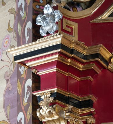 Zdjęcie nr 62: Nastawa architektoniczna, jednoosiowa, jednokondygnacyjna ze zwieńczeniem, na wysokim cokole z wyodrębnionymi konsolami. Ołtarz drewniany, sarkofagowy, na cokole, zwężający się ku dołowi z drewnianą mensą i kamiennym portatylem. Na mensie ustawione tabernakulum w formie prostopadłościennej skrzynki. Ścianka frontowa ujęta ornamentalnymi listewkami; drzwiczki w kształcie stojącego prostokąta w ornamentalnej ramie z płaskorzeźbionym przedstawieniem kielicha z hostią i winnym gronem. Nastawa ujęta parą zdwojonych pilastrów zwróconych pod kątem na zewnątrz, dekorowanych zwisami kwiatowymi, dźwigających silnie wysunięte imposty podtrzymywane przez konsole. Na tle pilastrów figury św. Antoniego Padewskiego i św. Franciszka ustawione na konsolach. W polu środkowym obraz św. Franciszka w formie stojącego prostokąta ujęty profilowaną ramą zdobioną rocaille'em. Powyżej wolutowe fragmenty rocaille'u, pod nim płycina. Zwieńczenie w formie trapezu ujętego spływami wolutowymi, dekorowanymi liśćmi palmowymi, ze ślimacznicami w kształcie meandru, spływającymi na belkowanie, na których stoją wazony. Całość zamknięta fragmentem wyłamanego trójbocznie gzymsu, zwieńczonego rokokowym szczytem z kwiatowymi gałązkami. W polu obraz św. Franciszki Rzymskiej w formie zbliżonej do zwieńczenia, ujęty ramą dekorowaną rocaille'em. Struktura polichromowana w kolorze głębokiej czerwieni, z czarnymi profilami oraz złoconymi ramami, profilami i ornamentyką.
