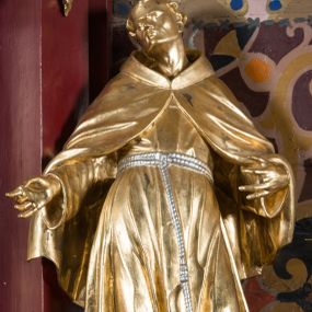 Zdjęcie nr 1: Rzeźba drążona, ustawiona na niewielkiej podstawie. Święty ukazany frontalnie z uniesioną głową, skierowaną w prawo, w kontrapoście, odchylony w tył. Obie ręce ma rozłożone na boki, a dłonie skierowane w prawo. Twarz ma szczupłą, kwadratową, z wyraźnie zarysowaną żuchwą, o migdałowatych, blisko siebie osadzonych oczach, małym nosie i ustach. Na głowie ma tonsurę, wokół krótkie, kręcone włosy. Ubrany jest w habit, ściśle przylegający do ciała, przepasany w talii podwójnym szczurem z końcem z jednym guzem oraz krótki płaszcz z kapturem zapięty na piersi i opadający na ramiona. Figura niemal w całości złocona, sznur srebrzony.