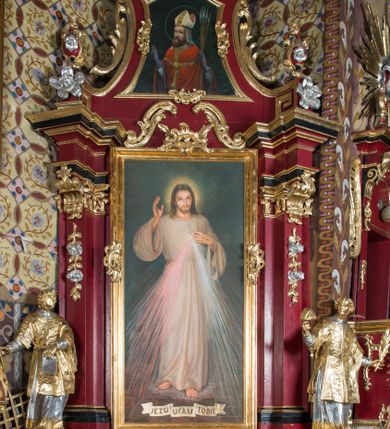 Zdjęcie nr 1: Nastawa architektoniczna, jednoosiowa, jednokondygnacyjna ze zwieńczeniem, na wysokim cokole z wyodrębnionymi konsolami. Ołtarz drewniany, sarkofagowy, na cokole, zwężający się ku dołowi z drewnianą mensą i kamiennym portatylem. Nastawa ujęta parą zdwojonych pilastrów zwróconych pod kątem na zewnątrz, dekorowanych zwisami kwiatowymi, dźwigających silnie wysunięte imposty podtrzymywane przez konsole. Na tle pilastrów figury św. Wawrzyńca i św. Szczepana ustawione na konsolach. Całe pole środkowe wypełnia wtórnie umieszczony obraz „Jezu ufam Tobie” w profilowanej ramie zdobionej rocaille'em. Nad nim fragmenty rocaille'u, pod nim płycina z dekoracją roślinną. Zwieńczenie w formie trapezu ujętego spływami wolutowymi, dekorowanymi liśćmi palmowymi, ze ślimacznicami w kształcie meandru, spływającymi na belkowanie, na których stoją wazony. Całość zamknięta fragmentem wyłamanego trójbocznie gzymsu, zwieńczonego rokokowym szczytem z kwiatowymi gałązkami. W polu obraz św. Wojciecha w formie zbliżonej do zwieńczenia, ujęty ramą dekorowaną rocaille'em. Struktura polichromowana w kolorze głębokiej czerwieni, z czarnymi profilami oraz złoconymi ramami, profilami i ornamentyką.
