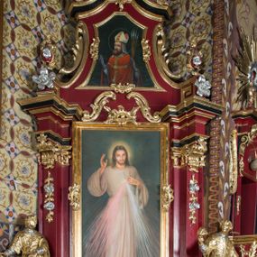 Zdjęcie nr 1: Nastawa architektoniczna, jednoosiowa, jednokondygnacyjna ze zwieńczeniem, na wysokim cokole z wyodrębnionymi konsolami. Ołtarz drewniany, sarkofagowy, na cokole, zwężający się ku dołowi z drewnianą mensą i kamiennym portatylem. Nastawa ujęta parą zdwojonych pilastrów zwróconych pod kątem na zewnątrz, dekorowanych zwisami kwiatowymi, dźwigających silnie wysunięte imposty podtrzymywane przez konsole. Na tle pilastrów figury św. Wawrzyńca i św. Szczepana ustawione na konsolach. Całe pole środkowe wypełnia wtórnie umieszczony obraz „Jezu ufam Tobie” w profilowanej ramie zdobionej rocaille&#039;em. Nad nim fragmenty rocaille&#039;u, pod nim płycina z dekoracją roślinną. Zwieńczenie w formie trapezu ujętego spływami wolutowymi, dekorowanymi liśćmi palmowymi, ze ślimacznicami w kształcie meandru, spływającymi na belkowanie, na których stoją wazony. Całość zamknięta fragmentem wyłamanego trójbocznie gzymsu, zwieńczonego rokokowym szczytem z kwiatowymi gałązkami. W polu obraz św. Wojciecha w formie zbliżonej do zwieńczenia, ujęty ramą dekorowaną rocaille&#039;em. Struktura polichromowana w kolorze głębokiej czerwieni, z czarnymi profilami oraz złoconymi ramami, profilami i ornamentyką.
