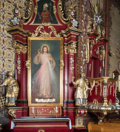 Zdjęcie nr 2: Nastawa architektoniczna, jednoosiowa, jednokondygnacyjna ze zwieńczeniem, na wysokim cokole z wyodrębnionymi konsolami. Ołtarz drewniany, sarkofagowy, na cokole, zwężający się ku dołowi z drewnianą mensą i kamiennym portatylem. Nastawa ujęta parą zdwojonych pilastrów zwróconych pod kątem na zewnątrz, dekorowanych zwisami kwiatowymi, dźwigających silnie wysunięte imposty podtrzymywane przez konsole. Na tle pilastrów figury św. Wawrzyńca i św. Szczepana ustawione na konsolach. Całe pole środkowe wypełnia wtórnie umieszczony obraz „Jezu ufam Tobie” w profilowanej ramie zdobionej rocaille'em. Nad nim fragmenty rocaille'u, pod nim płycina z dekoracją roślinną. Zwieńczenie w formie trapezu ujętego spływami wolutowymi, dekorowanymi liśćmi palmowymi, ze ślimacznicami w kształcie meandru, spływającymi na belkowanie, na których stoją wazony. Całość zamknięta fragmentem wyłamanego trójbocznie gzymsu, zwieńczonego rokokowym szczytem z kwiatowymi gałązkami. W polu obraz św. Wojciecha w formie zbliżonej do zwieńczenia, ujęty ramą dekorowaną rocaille'em. Struktura polichromowana w kolorze głębokiej czerwieni, z czarnymi profilami oraz złoconymi ramami, profilami i ornamentyką.
