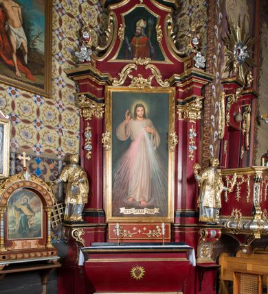 Zdjęcie nr 13: Nastawa architektoniczna, jednoosiowa, jednokondygnacyjna ze zwieńczeniem, na wysokim cokole z wyodrębnionymi konsolami. Ołtarz drewniany, sarkofagowy, na cokole, zwężający się ku dołowi z drewnianą mensą i kamiennym portatylem. Nastawa ujęta parą zdwojonych pilastrów zwróconych pod kątem na zewnątrz, dekorowanych zwisami kwiatowymi, dźwigających silnie wysunięte imposty podtrzymywane przez konsole. Na tle pilastrów figury św. Wawrzyńca i św. Szczepana ustawione na konsolach. Całe pole środkowe wypełnia wtórnie umieszczony obraz „Jezu ufam Tobie” w profilowanej ramie zdobionej rocaille'em. Nad nim fragmenty rocaille'u, pod nim płycina z dekoracją roślinną. Zwieńczenie w formie trapezu ujętego spływami wolutowymi, dekorowanymi liśćmi palmowymi, ze ślimacznicami w kształcie meandru, spływającymi na belkowanie, na których stoją wazony. Całość zamknięta fragmentem wyłamanego trójbocznie gzymsu, zwieńczonego rokokowym szczytem z kwiatowymi gałązkami. W polu obraz św. Wojciecha w formie zbliżonej do zwieńczenia, ujęty ramą dekorowaną rocaille'em. Struktura polichromowana w kolorze głębokiej czerwieni, z czarnymi profilami oraz złoconymi ramami, profilami i ornamentyką.
