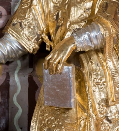 Zdjęcie nr 35: Nastawa architektoniczna, jednoosiowa, jednokondygnacyjna ze zwieńczeniem, na wysokim cokole z wyodrębnionymi konsolami. Ołtarz drewniany, sarkofagowy, na cokole, zwężający się ku dołowi z drewnianą mensą i kamiennym portatylem. Nastawa ujęta parą zdwojonych pilastrów zwróconych pod kątem na zewnątrz, dekorowanych zwisami kwiatowymi, dźwigających silnie wysunięte imposty podtrzymywane przez konsole. Na tle pilastrów figury św. Wawrzyńca i św. Szczepana ustawione na konsolach. Całe pole środkowe wypełnia wtórnie umieszczony obraz „Jezu ufam Tobie” w profilowanej ramie zdobionej rocaille&#039;em. Nad nim fragmenty rocaille&#039;u, pod nim płycina z dekoracją roślinną. Zwieńczenie w formie trapezu ujętego spływami wolutowymi, dekorowanymi liśćmi palmowymi, ze ślimacznicami w kształcie meandru, spływającymi na belkowanie, na których stoją wazony. Całość zamknięta fragmentem wyłamanego trójbocznie gzymsu, zwieńczonego rokokowym szczytem z kwiatowymi gałązkami. W polu obraz św. Wojciecha w formie zbliżonej do zwieńczenia, ujęty ramą dekorowaną rocaille&#039;em. Struktura polichromowana w kolorze głębokiej czerwieni, z czarnymi profilami oraz złoconymi ramami, profilami i ornamentyką.
