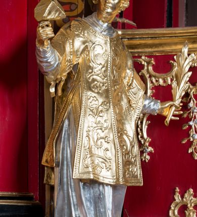 Zdjęcie nr 17: Nastawa architektoniczna, jednoosiowa, jednokondygnacyjna ze zwieńczeniem, na wysokim cokole z wyodrębnionymi konsolami. Ołtarz drewniany, sarkofagowy, na cokole, zwężający się ku dołowi z drewnianą mensą i kamiennym portatylem. Nastawa ujęta parą zdwojonych pilastrów zwróconych pod kątem na zewnątrz, dekorowanych zwisami kwiatowymi, dźwigających silnie wysunięte imposty podtrzymywane przez konsole. Na tle pilastrów figury św. Wawrzyńca i św. Szczepana ustawione na konsolach. Całe pole środkowe wypełnia wtórnie umieszczony obraz „Jezu ufam Tobie” w profilowanej ramie zdobionej rocaille'em. Nad nim fragmenty rocaille'u, pod nim płycina z dekoracją roślinną. Zwieńczenie w formie trapezu ujętego spływami wolutowymi, dekorowanymi liśćmi palmowymi, ze ślimacznicami w kształcie meandru, spływającymi na belkowanie, na których stoją wazony. Całość zamknięta fragmentem wyłamanego trójbocznie gzymsu, zwieńczonego rokokowym szczytem z kwiatowymi gałązkami. W polu obraz św. Wojciecha w formie zbliżonej do zwieńczenia, ujęty ramą dekorowaną rocaille'em. Struktura polichromowana w kolorze głębokiej czerwieni, z czarnymi profilami oraz złoconymi ramami, profilami i ornamentyką.
