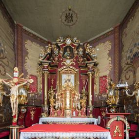 Zdjęcie nr 1: Nastawa architektoniczna, jednoosiowa, jednokondygnacyjna ze zwieńczeniem, ustawiona na dwustrefowym cokole z wyodrębnionymi prostopadłościanami. Ołtarz drewniany, prostopadłościenny z drewnianą mensą. Antepedium wydzielone ramą i wysunięte do przodu, ujęte pilastrami dźwigającymi niepełne belkowanie, w polu wieniec laurowy z rozetą, nad nim kokarda z karbowanej wstęgi flankowana przez dwa podwieszone festony z tkaniny, poniżej wić roślinna. Na ołtarzu ustawione tabernakulum w formie metalowej skrzynki w drewnianej obudowie, ujęte ustawionymi pod kątem spływami wolutowymi. Ścianka frontowa wypukła, z drewnianymi drzwiczkami w kształcie stojącego prostokąta zamkniętego łukiem półkolistym z płaskorzeźbionym kielichem z hostią i kłosami zbóż. Na nim wysoki tron wystawienia z wypukłym frontem z zamontowanym wtórnie nowym tabernakulum (wcześniej obrotowa nisza). Tron ujęty pilastrami ustawionymi pod kątem, o trzonach przechodzących w spływy wolutowe, dekorowane zwisami kwiatowymi; zwieńczony jest trzema rocaille'owymi kabłąkami dekorowanymi zwisami kwiatowymi, podtrzymującymi figurkę pelikana karmiącego młode w gnieździe. Tabernakulum i tron flankowane spływami z podwieszonymi zwisami kwiatowymi zakończonymi cokołami, dźwigającymi przerwany wolutowy przyczółek z figurkami adorujących aniołów; spływy w górnej części zamknięte fragmentami gzymsu z palmetami. 
Nastawa ujęta dwiema parami pilastrów oraz stojącą na ich tle parą kolumn na cokołach dźwigających pełne belkowanie przerwane nad polem środkowym oraz fragmenty przerwanego, wolutowego przyczółka. Przed wewnętrzną parą pilastrów ustawione figury św. Piotra i św. Pawła; na belkowaniu wazony, na przyczółku putta trzymające słońce i księżyc. W polu środkowym podwójna wnęka w formie stojącego prostokąta zamkniętego łukiem odcinkowym nadwieszonym, ujęta profilowaną ramą, ze znacznie mniejszym obrazem Matki Boskiej w kształcie stojącego prostokąta. Nad nią medalion utworzony z wolut i zwisów, zwieńczony koroną otwartą. Zwieńczenie nastawy w formie trapezu ujętego wolutami spływającymi na belkowanie, zamknięte fragmentem falistego gzymsu, dekorowanym medalionem z Okiem Opatrzności w otoku z obłoków w glorii promienistej oraz gałązkami kwiatowymi. W polu obraz św. Katarzyny w formie zbliżonej do zwieńczenia, o ściętych dolnych narożach, w profilowanej ramie, z gałązkami kwiatowymi. 
Nastawa flankowana uszami utworzonymi z rocaille'u, przytwierdzonymi do ściany. Ujęta parą wsporników na trumienki relikwiarzowe oraz parą dużych konsol dekorowanych rocaille'm z figurami św. Mikołaja i św. Stanisława. Struktura polichromowana w kolorze głębokiej czerwieni z czarnymi profilami; kolumny, ornamentyka i profile złocone i srebrzone.