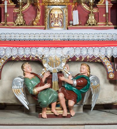 Zdjęcie nr 3: Nastawa architektoniczna, jednoosiowa, jednokondygnacyjna ze zwieńczeniem, ustawiona na dwustrefowym cokole z wyodrębnionymi prostopadłościanami. Ołtarz drewniany, prostopadłościenny z drewnianą mensą. Antepedium wydzielone ramą i wysunięte do przodu, ujęte pilastrami dźwigającymi niepełne belkowanie, w polu wieniec laurowy z rozetą, nad nim kokarda z karbowanej wstęgi flankowana przez dwa podwieszone festony z tkaniny, poniżej wić roślinna. Na ołtarzu ustawione tabernakulum w formie metalowej skrzynki w drewnianej obudowie, ujęte ustawionymi pod kątem spływami wolutowymi. Ścianka frontowa wypukła, z drewnianymi drzwiczkami w kształcie stojącego prostokąta zamkniętego łukiem półkolistym z płaskorzeźbionym kielichem z hostią i kłosami zbóż. Na nim wysoki tron wystawienia z wypukłym frontem z zamontowanym wtórnie nowym tabernakulum (wcześniej obrotowa nisza). Tron ujęty pilastrami ustawionymi pod kątem, o trzonach przechodzących w spływy wolutowe, dekorowane zwisami kwiatowymi; zwieńczony jest trzema rocaille&#039;owymi kabłąkami dekorowanymi zwisami kwiatowymi, podtrzymującymi figurkę pelikana karmiącego młode w gnieździe. Tabernakulum i tron flankowane spływami z podwieszonymi zwisami kwiatowymi zakończonymi cokołami, dźwigającymi przerwany wolutowy przyczółek z figurkami adorujących aniołów; spływy w górnej części zamknięte fragmentami gzymsu z palmetami. 
Nastawa ujęta dwiema parami pilastrów oraz stojącą na ich tle parą kolumn na cokołach dźwigających pełne belkowanie przerwane nad polem środkowym oraz fragmenty przerwanego, wolutowego przyczółka. Przed wewnętrzną parą pilastrów ustawione figury św. Piotra i św. Pawła; na belkowaniu wazony, na przyczółku putta trzymające słońce i księżyc. W polu środkowym podwójna wnęka w formie stojącego prostokąta zamkniętego łukiem odcinkowym nadwieszonym, ujęta profilowaną ramą, ze znacznie mniejszym obrazem Matki Boskiej w kształcie stojącego prostokąta. Nad nią medalion utworzony z wolut i zwisów, zwieńczony koroną otwartą. Zwieńczenie nastawy w formie trapezu ujętego wolutami spływającymi na belkowanie, zamknięte fragmentem falistego gzymsu, dekorowanym medalionem z Okiem Opatrzności w otoku z obłoków w glorii promienistej oraz gałązkami kwiatowymi. W polu obraz św. Katarzyny w formie zbliżonej do zwieńczenia, o ściętych dolnych narożach, w profilowanej ramie, z gałązkami kwiatowymi. 
Nastawa flankowana uszami utworzonymi z rocaille&#039;u, przytwierdzonymi do ściany. Ujęta parą wsporników na trumienki relikwiarzowe oraz parą dużych konsol dekorowanych rocaille&#039;m z figurami św. Mikołaja i św. Stanisława. Struktura polichromowana w kolorze głębokiej czerwieni z czarnymi profilami; kolumny, ornamentyka i profile złocone i srebrzone.