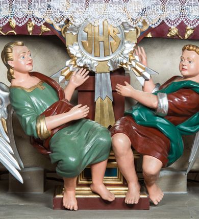 Zdjęcie nr 4: Nastawa architektoniczna, jednoosiowa, jednokondygnacyjna ze zwieńczeniem, ustawiona na dwustrefowym cokole z wyodrębnionymi prostopadłościanami. Ołtarz drewniany, prostopadłościenny z drewnianą mensą. Antepedium wydzielone ramą i wysunięte do przodu, ujęte pilastrami dźwigającymi niepełne belkowanie, w polu wieniec laurowy z rozetą, nad nim kokarda z karbowanej wstęgi flankowana przez dwa podwieszone festony z tkaniny, poniżej wić roślinna. Na ołtarzu ustawione tabernakulum w formie metalowej skrzynki w drewnianej obudowie, ujęte ustawionymi pod kątem spływami wolutowymi. Ścianka frontowa wypukła, z drewnianymi drzwiczkami w kształcie stojącego prostokąta zamkniętego łukiem półkolistym z płaskorzeźbionym kielichem z hostią i kłosami zbóż. Na nim wysoki tron wystawienia z wypukłym frontem z zamontowanym wtórnie nowym tabernakulum (wcześniej obrotowa nisza). Tron ujęty pilastrami ustawionymi pod kątem, o trzonach przechodzących w spływy wolutowe, dekorowane zwisami kwiatowymi; zwieńczony jest trzema rocaille'owymi kabłąkami dekorowanymi zwisami kwiatowymi, podtrzymującymi figurkę pelikana karmiącego młode w gnieździe. Tabernakulum i tron flankowane spływami z podwieszonymi zwisami kwiatowymi zakończonymi cokołami, dźwigającymi przerwany wolutowy przyczółek z figurkami adorujących aniołów; spływy w górnej części zamknięte fragmentami gzymsu z palmetami. 
Nastawa ujęta dwiema parami pilastrów oraz stojącą na ich tle parą kolumn na cokołach dźwigających pełne belkowanie przerwane nad polem środkowym oraz fragmenty przerwanego, wolutowego przyczółka. Przed wewnętrzną parą pilastrów ustawione figury św. Piotra i św. Pawła; na belkowaniu wazony, na przyczółku putta trzymające słońce i księżyc. W polu środkowym podwójna wnęka w formie stojącego prostokąta zamkniętego łukiem odcinkowym nadwieszonym, ujęta profilowaną ramą, ze znacznie mniejszym obrazem Matki Boskiej w kształcie stojącego prostokąta. Nad nią medalion utworzony z wolut i zwisów, zwieńczony koroną otwartą. Zwieńczenie nastawy w formie trapezu ujętego wolutami spływającymi na belkowanie, zamknięte fragmentem falistego gzymsu, dekorowanym medalionem z Okiem Opatrzności w otoku z obłoków w glorii promienistej oraz gałązkami kwiatowymi. W polu obraz św. Katarzyny w formie zbliżonej do zwieńczenia, o ściętych dolnych narożach, w profilowanej ramie, z gałązkami kwiatowymi. 
Nastawa flankowana uszami utworzonymi z rocaille'u, przytwierdzonymi do ściany. Ujęta parą wsporników na trumienki relikwiarzowe oraz parą dużych konsol dekorowanych rocaille'm z figurami św. Mikołaja i św. Stanisława. Struktura polichromowana w kolorze głębokiej czerwieni z czarnymi profilami; kolumny, ornamentyka i profile złocone i srebrzone.