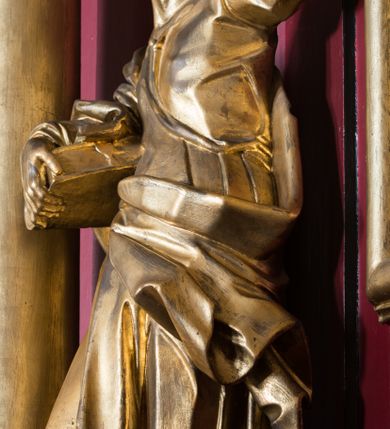 Zdjęcie nr 23: Nastawa architektoniczna, jednoosiowa, jednokondygnacyjna ze zwieńczeniem, ustawiona na dwustrefowym cokole z wyodrębnionymi prostopadłościanami. Ołtarz drewniany, prostopadłościenny z drewnianą mensą. Antepedium wydzielone ramą i wysunięte do przodu, ujęte pilastrami dźwigającymi niepełne belkowanie, w polu wieniec laurowy z rozetą, nad nim kokarda z karbowanej wstęgi flankowana przez dwa podwieszone festony z tkaniny, poniżej wić roślinna. Na ołtarzu ustawione tabernakulum w formie metalowej skrzynki w drewnianej obudowie, ujęte ustawionymi pod kątem spływami wolutowymi. Ścianka frontowa wypukła, z drewnianymi drzwiczkami w kształcie stojącego prostokąta zamkniętego łukiem półkolistym z płaskorzeźbionym kielichem z hostią i kłosami zbóż. Na nim wysoki tron wystawienia z wypukłym frontem z zamontowanym wtórnie nowym tabernakulum (wcześniej obrotowa nisza). Tron ujęty pilastrami ustawionymi pod kątem, o trzonach przechodzących w spływy wolutowe, dekorowane zwisami kwiatowymi; zwieńczony jest trzema rocaille&#039;owymi kabłąkami dekorowanymi zwisami kwiatowymi, podtrzymującymi figurkę pelikana karmiącego młode w gnieździe. Tabernakulum i tron flankowane spływami z podwieszonymi zwisami kwiatowymi zakończonymi cokołami, dźwigającymi przerwany wolutowy przyczółek z figurkami adorujących aniołów; spływy w górnej części zamknięte fragmentami gzymsu z palmetami. 
Nastawa ujęta dwiema parami pilastrów oraz stojącą na ich tle parą kolumn na cokołach dźwigających pełne belkowanie przerwane nad polem środkowym oraz fragmenty przerwanego, wolutowego przyczółka. Przed wewnętrzną parą pilastrów ustawione figury św. Piotra i św. Pawła; na belkowaniu wazony, na przyczółku putta trzymające słońce i księżyc. W polu środkowym podwójna wnęka w formie stojącego prostokąta zamkniętego łukiem odcinkowym nadwieszonym, ujęta profilowaną ramą, ze znacznie mniejszym obrazem Matki Boskiej w kształcie stojącego prostokąta. Nad nią medalion utworzony z wolut i zwisów, zwieńczony koroną otwartą. Zwieńczenie nastawy w formie trapezu ujętego wolutami spływającymi na belkowanie, zamknięte fragmentem falistego gzymsu, dekorowanym medalionem z Okiem Opatrzności w otoku z obłoków w glorii promienistej oraz gałązkami kwiatowymi. W polu obraz św. Katarzyny w formie zbliżonej do zwieńczenia, o ściętych dolnych narożach, w profilowanej ramie, z gałązkami kwiatowymi. 
Nastawa flankowana uszami utworzonymi z rocaille&#039;u, przytwierdzonymi do ściany. Ujęta parą wsporników na trumienki relikwiarzowe oraz parą dużych konsol dekorowanych rocaille&#039;m z figurami św. Mikołaja i św. Stanisława. Struktura polichromowana w kolorze głębokiej czerwieni z czarnymi profilami; kolumny, ornamentyka i profile złocone i srebrzone.