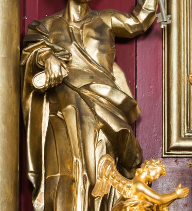 Zdjęcie nr 32: Nastawa architektoniczna, jednoosiowa, jednokondygnacyjna ze zwieńczeniem, ustawiona na dwustrefowym cokole z wyodrębnionymi prostopadłościanami. Ołtarz drewniany, prostopadłościenny z drewnianą mensą. Antepedium wydzielone ramą i wysunięte do przodu, ujęte pilastrami dźwigającymi niepełne belkowanie, w polu wieniec laurowy z rozetą, nad nim kokarda z karbowanej wstęgi flankowana przez dwa podwieszone festony z tkaniny, poniżej wić roślinna. Na ołtarzu ustawione tabernakulum w formie metalowej skrzynki w drewnianej obudowie, ujęte ustawionymi pod kątem spływami wolutowymi. Ścianka frontowa wypukła, z drewnianymi drzwiczkami w kształcie stojącego prostokąta zamkniętego łukiem półkolistym z płaskorzeźbionym kielichem z hostią i kłosami zbóż. Na nim wysoki tron wystawienia z wypukłym frontem z zamontowanym wtórnie nowym tabernakulum (wcześniej obrotowa nisza). Tron ujęty pilastrami ustawionymi pod kątem, o trzonach przechodzących w spływy wolutowe, dekorowane zwisami kwiatowymi; zwieńczony jest trzema rocaille&#039;owymi kabłąkami dekorowanymi zwisami kwiatowymi, podtrzymującymi figurkę pelikana karmiącego młode w gnieździe. Tabernakulum i tron flankowane spływami z podwieszonymi zwisami kwiatowymi zakończonymi cokołami, dźwigającymi przerwany wolutowy przyczółek z figurkami adorujących aniołów; spływy w górnej części zamknięte fragmentami gzymsu z palmetami. 
Nastawa ujęta dwiema parami pilastrów oraz stojącą na ich tle parą kolumn na cokołach dźwigających pełne belkowanie przerwane nad polem środkowym oraz fragmenty przerwanego, wolutowego przyczółka. Przed wewnętrzną parą pilastrów ustawione figury św. Piotra i św. Pawła; na belkowaniu wazony, na przyczółku putta trzymające słońce i księżyc. W polu środkowym podwójna wnęka w formie stojącego prostokąta zamkniętego łukiem odcinkowym nadwieszonym, ujęta profilowaną ramą, ze znacznie mniejszym obrazem Matki Boskiej w kształcie stojącego prostokąta. Nad nią medalion utworzony z wolut i zwisów, zwieńczony koroną otwartą. Zwieńczenie nastawy w formie trapezu ujętego wolutami spływającymi na belkowanie, zamknięte fragmentem falistego gzymsu, dekorowanym medalionem z Okiem Opatrzności w otoku z obłoków w glorii promienistej oraz gałązkami kwiatowymi. W polu obraz św. Katarzyny w formie zbliżonej do zwieńczenia, o ściętych dolnych narożach, w profilowanej ramie, z gałązkami kwiatowymi. 
Nastawa flankowana uszami utworzonymi z rocaille&#039;u, przytwierdzonymi do ściany. Ujęta parą wsporników na trumienki relikwiarzowe oraz parą dużych konsol dekorowanych rocaille&#039;m z figurami św. Mikołaja i św. Stanisława. Struktura polichromowana w kolorze głębokiej czerwieni z czarnymi profilami; kolumny, ornamentyka i profile złocone i srebrzone.