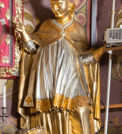 Zdjęcie nr 56: Nastawa architektoniczna, jednoosiowa, jednokondygnacyjna ze zwieńczeniem, ustawiona na dwustrefowym cokole z wyodrębnionymi prostopadłościanami. Ołtarz drewniany, prostopadłościenny z drewnianą mensą. Antepedium wydzielone ramą i wysunięte do przodu, ujęte pilastrami dźwigającymi niepełne belkowanie, w polu wieniec laurowy z rozetą, nad nim kokarda z karbowanej wstęgi flankowana przez dwa podwieszone festony z tkaniny, poniżej wić roślinna. Na ołtarzu ustawione tabernakulum w formie metalowej skrzynki w drewnianej obudowie, ujęte ustawionymi pod kątem spływami wolutowymi. Ścianka frontowa wypukła, z drewnianymi drzwiczkami w kształcie stojącego prostokąta zamkniętego łukiem półkolistym z płaskorzeźbionym kielichem z hostią i kłosami zbóż. Na nim wysoki tron wystawienia z wypukłym frontem z zamontowanym wtórnie nowym tabernakulum (wcześniej obrotowa nisza). Tron ujęty pilastrami ustawionymi pod kątem, o trzonach przechodzących w spływy wolutowe, dekorowane zwisami kwiatowymi; zwieńczony jest trzema rocaille&#039;owymi kabłąkami dekorowanymi zwisami kwiatowymi, podtrzymującymi figurkę pelikana karmiącego młode w gnieździe. Tabernakulum i tron flankowane spływami z podwieszonymi zwisami kwiatowymi zakończonymi cokołami, dźwigającymi przerwany wolutowy przyczółek z figurkami adorujących aniołów; spływy w górnej części zamknięte fragmentami gzymsu z palmetami. 
Nastawa ujęta dwiema parami pilastrów oraz stojącą na ich tle parą kolumn na cokołach dźwigających pełne belkowanie przerwane nad polem środkowym oraz fragmenty przerwanego, wolutowego przyczółka. Przed wewnętrzną parą pilastrów ustawione figury św. Piotra i św. Pawła; na belkowaniu wazony, na przyczółku putta trzymające słońce i księżyc. W polu środkowym podwójna wnęka w formie stojącego prostokąta zamkniętego łukiem odcinkowym nadwieszonym, ujęta profilowaną ramą, ze znacznie mniejszym obrazem Matki Boskiej w kształcie stojącego prostokąta. Nad nią medalion utworzony z wolut i zwisów, zwieńczony koroną otwartą. Zwieńczenie nastawy w formie trapezu ujętego wolutami spływającymi na belkowanie, zamknięte fragmentem falistego gzymsu, dekorowanym medalionem z Okiem Opatrzności w otoku z obłoków w glorii promienistej oraz gałązkami kwiatowymi. W polu obraz św. Katarzyny w formie zbliżonej do zwieńczenia, o ściętych dolnych narożach, w profilowanej ramie, z gałązkami kwiatowymi. 
Nastawa flankowana uszami utworzonymi z rocaille&#039;u, przytwierdzonymi do ściany. Ujęta parą wsporników na trumienki relikwiarzowe oraz parą dużych konsol dekorowanych rocaille&#039;m z figurami św. Mikołaja i św. Stanisława. Struktura polichromowana w kolorze głębokiej czerwieni z czarnymi profilami; kolumny, ornamentyka i profile złocone i srebrzone.