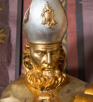 Zdjęcie nr 74: Nastawa architektoniczna, jednoosiowa, jednokondygnacyjna ze zwieńczeniem, ustawiona na dwustrefowym cokole z wyodrębnionymi prostopadłościanami. Ołtarz drewniany, prostopadłościenny z drewnianą mensą. Antepedium wydzielone ramą i wysunięte do przodu, ujęte pilastrami dźwigającymi niepełne belkowanie, w polu wieniec laurowy z rozetą, nad nim kokarda z karbowanej wstęgi flankowana przez dwa podwieszone festony z tkaniny, poniżej wić roślinna. Na ołtarzu ustawione tabernakulum w formie metalowej skrzynki w drewnianej obudowie, ujęte ustawionymi pod kątem spływami wolutowymi. Ścianka frontowa wypukła, z drewnianymi drzwiczkami w kształcie stojącego prostokąta zamkniętego łukiem półkolistym z płaskorzeźbionym kielichem z hostią i kłosami zbóż. Na nim wysoki tron wystawienia z wypukłym frontem z zamontowanym wtórnie nowym tabernakulum (wcześniej obrotowa nisza). Tron ujęty pilastrami ustawionymi pod kątem, o trzonach przechodzących w spływy wolutowe, dekorowane zwisami kwiatowymi; zwieńczony jest trzema rocaille&#039;owymi kabłąkami dekorowanymi zwisami kwiatowymi, podtrzymującymi figurkę pelikana karmiącego młode w gnieździe. Tabernakulum i tron flankowane spływami z podwieszonymi zwisami kwiatowymi zakończonymi cokołami, dźwigającymi przerwany wolutowy przyczółek z figurkami adorujących aniołów; spływy w górnej części zamknięte fragmentami gzymsu z palmetami. 
Nastawa ujęta dwiema parami pilastrów oraz stojącą na ich tle parą kolumn na cokołach dźwigających pełne belkowanie przerwane nad polem środkowym oraz fragmenty przerwanego, wolutowego przyczółka. Przed wewnętrzną parą pilastrów ustawione figury św. Piotra i św. Pawła; na belkowaniu wazony, na przyczółku putta trzymające słońce i księżyc. W polu środkowym podwójna wnęka w formie stojącego prostokąta zamkniętego łukiem odcinkowym nadwieszonym, ujęta profilowaną ramą, ze znacznie mniejszym obrazem Matki Boskiej w kształcie stojącego prostokąta. Nad nią medalion utworzony z wolut i zwisów, zwieńczony koroną otwartą. Zwieńczenie nastawy w formie trapezu ujętego wolutami spływającymi na belkowanie, zamknięte fragmentem falistego gzymsu, dekorowanym medalionem z Okiem Opatrzności w otoku z obłoków w glorii promienistej oraz gałązkami kwiatowymi. W polu obraz św. Katarzyny w formie zbliżonej do zwieńczenia, o ściętych dolnych narożach, w profilowanej ramie, z gałązkami kwiatowymi. 
Nastawa flankowana uszami utworzonymi z rocaille&#039;u, przytwierdzonymi do ściany. Ujęta parą wsporników na trumienki relikwiarzowe oraz parą dużych konsol dekorowanych rocaille&#039;m z figurami św. Mikołaja i św. Stanisława. Struktura polichromowana w kolorze głębokiej czerwieni z czarnymi profilami; kolumny, ornamentyka i profile złocone i srebrzone.