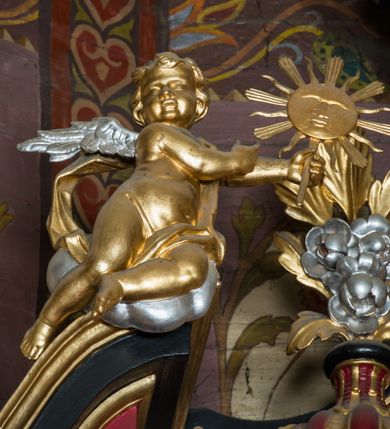 Zdjęcie nr 86: Nastawa architektoniczna, jednoosiowa, jednokondygnacyjna ze zwieńczeniem, ustawiona na dwustrefowym cokole z wyodrębnionymi prostopadłościanami. Ołtarz drewniany, prostopadłościenny z drewnianą mensą. Antepedium wydzielone ramą i wysunięte do przodu, ujęte pilastrami dźwigającymi niepełne belkowanie, w polu wieniec laurowy z rozetą, nad nim kokarda z karbowanej wstęgi flankowana przez dwa podwieszone festony z tkaniny, poniżej wić roślinna. Na ołtarzu ustawione tabernakulum w formie metalowej skrzynki w drewnianej obudowie, ujęte ustawionymi pod kątem spływami wolutowymi. Ścianka frontowa wypukła, z drewnianymi drzwiczkami w kształcie stojącego prostokąta zamkniętego łukiem półkolistym z płaskorzeźbionym kielichem z hostią i kłosami zbóż. Na nim wysoki tron wystawienia z wypukłym frontem z zamontowanym wtórnie nowym tabernakulum (wcześniej obrotowa nisza). Tron ujęty pilastrami ustawionymi pod kątem, o trzonach przechodzących w spływy wolutowe, dekorowane zwisami kwiatowymi; zwieńczony jest trzema rocaille'owymi kabłąkami dekorowanymi zwisami kwiatowymi, podtrzymującymi figurkę pelikana karmiącego młode w gnieździe. Tabernakulum i tron flankowane spływami z podwieszonymi zwisami kwiatowymi zakończonymi cokołami, dźwigającymi przerwany wolutowy przyczółek z figurkami adorujących aniołów; spływy w górnej części zamknięte fragmentami gzymsu z palmetami. 
Nastawa ujęta dwiema parami pilastrów oraz stojącą na ich tle parą kolumn na cokołach dźwigających pełne belkowanie przerwane nad polem środkowym oraz fragmenty przerwanego, wolutowego przyczółka. Przed wewnętrzną parą pilastrów ustawione figury św. Piotra i św. Pawła; na belkowaniu wazony, na przyczółku putta trzymające słońce i księżyc. W polu środkowym podwójna wnęka w formie stojącego prostokąta zamkniętego łukiem odcinkowym nadwieszonym, ujęta profilowaną ramą, ze znacznie mniejszym obrazem Matki Boskiej w kształcie stojącego prostokąta. Nad nią medalion utworzony z wolut i zwisów, zwieńczony koroną otwartą. Zwieńczenie nastawy w formie trapezu ujętego wolutami spływającymi na belkowanie, zamknięte fragmentem falistego gzymsu, dekorowanym medalionem z Okiem Opatrzności w otoku z obłoków w glorii promienistej oraz gałązkami kwiatowymi. W polu obraz św. Katarzyny w formie zbliżonej do zwieńczenia, o ściętych dolnych narożach, w profilowanej ramie, z gałązkami kwiatowymi. 
Nastawa flankowana uszami utworzonymi z rocaille'u, przytwierdzonymi do ściany. Ujęta parą wsporników na trumienki relikwiarzowe oraz parą dużych konsol dekorowanych rocaille'm z figurami św. Mikołaja i św. Stanisława. Struktura polichromowana w kolorze głębokiej czerwieni z czarnymi profilami; kolumny, ornamentyka i profile złocone i srebrzone.