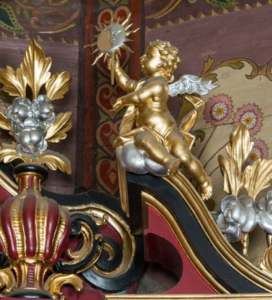 Zdjęcie nr 88: Nastawa architektoniczna, jednoosiowa, jednokondygnacyjna ze zwieńczeniem, ustawiona na dwustrefowym cokole z wyodrębnionymi prostopadłościanami. Ołtarz drewniany, prostopadłościenny z drewnianą mensą. Antepedium wydzielone ramą i wysunięte do przodu, ujęte pilastrami dźwigającymi niepełne belkowanie, w polu wieniec laurowy z rozetą, nad nim kokarda z karbowanej wstęgi flankowana przez dwa podwieszone festony z tkaniny, poniżej wić roślinna. Na ołtarzu ustawione tabernakulum w formie metalowej skrzynki w drewnianej obudowie, ujęte ustawionymi pod kątem spływami wolutowymi. Ścianka frontowa wypukła, z drewnianymi drzwiczkami w kształcie stojącego prostokąta zamkniętego łukiem półkolistym z płaskorzeźbionym kielichem z hostią i kłosami zbóż. Na nim wysoki tron wystawienia z wypukłym frontem z zamontowanym wtórnie nowym tabernakulum (wcześniej obrotowa nisza). Tron ujęty pilastrami ustawionymi pod kątem, o trzonach przechodzących w spływy wolutowe, dekorowane zwisami kwiatowymi; zwieńczony jest trzema rocaille&#039;owymi kabłąkami dekorowanymi zwisami kwiatowymi, podtrzymującymi figurkę pelikana karmiącego młode w gnieździe. Tabernakulum i tron flankowane spływami z podwieszonymi zwisami kwiatowymi zakończonymi cokołami, dźwigającymi przerwany wolutowy przyczółek z figurkami adorujących aniołów; spływy w górnej części zamknięte fragmentami gzymsu z palmetami. 
Nastawa ujęta dwiema parami pilastrów oraz stojącą na ich tle parą kolumn na cokołach dźwigających pełne belkowanie przerwane nad polem środkowym oraz fragmenty przerwanego, wolutowego przyczółka. Przed wewnętrzną parą pilastrów ustawione figury św. Piotra i św. Pawła; na belkowaniu wazony, na przyczółku putta trzymające słońce i księżyc. W polu środkowym podwójna wnęka w formie stojącego prostokąta zamkniętego łukiem odcinkowym nadwieszonym, ujęta profilowaną ramą, ze znacznie mniejszym obrazem Matki Boskiej w kształcie stojącego prostokąta. Nad nią medalion utworzony z wolut i zwisów, zwieńczony koroną otwartą. Zwieńczenie nastawy w formie trapezu ujętego wolutami spływającymi na belkowanie, zamknięte fragmentem falistego gzymsu, dekorowanym medalionem z Okiem Opatrzności w otoku z obłoków w glorii promienistej oraz gałązkami kwiatowymi. W polu obraz św. Katarzyny w formie zbliżonej do zwieńczenia, o ściętych dolnych narożach, w profilowanej ramie, z gałązkami kwiatowymi. 
Nastawa flankowana uszami utworzonymi z rocaille&#039;u, przytwierdzonymi do ściany. Ujęta parą wsporników na trumienki relikwiarzowe oraz parą dużych konsol dekorowanych rocaille&#039;m z figurami św. Mikołaja i św. Stanisława. Struktura polichromowana w kolorze głębokiej czerwieni z czarnymi profilami; kolumny, ornamentyka i profile złocone i srebrzone.