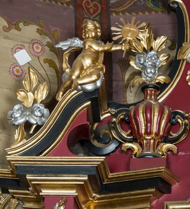 Zdjęcie nr 91: Nastawa architektoniczna, jednoosiowa, jednokondygnacyjna ze zwieńczeniem, ustawiona na dwustrefowym cokole z wyodrębnionymi prostopadłościanami. Ołtarz drewniany, prostopadłościenny z drewnianą mensą. Antepedium wydzielone ramą i wysunięte do przodu, ujęte pilastrami dźwigającymi niepełne belkowanie, w polu wieniec laurowy z rozetą, nad nim kokarda z karbowanej wstęgi flankowana przez dwa podwieszone festony z tkaniny, poniżej wić roślinna. Na ołtarzu ustawione tabernakulum w formie metalowej skrzynki w drewnianej obudowie, ujęte ustawionymi pod kątem spływami wolutowymi. Ścianka frontowa wypukła, z drewnianymi drzwiczkami w kształcie stojącego prostokąta zamkniętego łukiem półkolistym z płaskorzeźbionym kielichem z hostią i kłosami zbóż. Na nim wysoki tron wystawienia z wypukłym frontem z zamontowanym wtórnie nowym tabernakulum (wcześniej obrotowa nisza). Tron ujęty pilastrami ustawionymi pod kątem, o trzonach przechodzących w spływy wolutowe, dekorowane zwisami kwiatowymi; zwieńczony jest trzema rocaille'owymi kabłąkami dekorowanymi zwisami kwiatowymi, podtrzymującymi figurkę pelikana karmiącego młode w gnieździe. Tabernakulum i tron flankowane spływami z podwieszonymi zwisami kwiatowymi zakończonymi cokołami, dźwigającymi przerwany wolutowy przyczółek z figurkami adorujących aniołów; spływy w górnej części zamknięte fragmentami gzymsu z palmetami. 
Nastawa ujęta dwiema parami pilastrów oraz stojącą na ich tle parą kolumn na cokołach dźwigających pełne belkowanie przerwane nad polem środkowym oraz fragmenty przerwanego, wolutowego przyczółka. Przed wewnętrzną parą pilastrów ustawione figury św. Piotra i św. Pawła; na belkowaniu wazony, na przyczółku putta trzymające słońce i księżyc. W polu środkowym podwójna wnęka w formie stojącego prostokąta zamkniętego łukiem odcinkowym nadwieszonym, ujęta profilowaną ramą, ze znacznie mniejszym obrazem Matki Boskiej w kształcie stojącego prostokąta. Nad nią medalion utworzony z wolut i zwisów, zwieńczony koroną otwartą. Zwieńczenie nastawy w formie trapezu ujętego wolutami spływającymi na belkowanie, zamknięte fragmentem falistego gzymsu, dekorowanym medalionem z Okiem Opatrzności w otoku z obłoków w glorii promienistej oraz gałązkami kwiatowymi. W polu obraz św. Katarzyny w formie zbliżonej do zwieńczenia, o ściętych dolnych narożach, w profilowanej ramie, z gałązkami kwiatowymi. 
Nastawa flankowana uszami utworzonymi z rocaille'u, przytwierdzonymi do ściany. Ujęta parą wsporników na trumienki relikwiarzowe oraz parą dużych konsol dekorowanych rocaille'm z figurami św. Mikołaja i św. Stanisława. Struktura polichromowana w kolorze głębokiej czerwieni z czarnymi profilami; kolumny, ornamentyka i profile złocone i srebrzone.