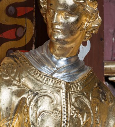 Zdjęcie nr 9: Rzeźba ścięta z tyłu i drążona, ustawiona na niskiej podstawie. Święty ukazany frontalnie, z głową skierowaną w prawo, w kontrapoście, o sylwetce lekko przechylonej w tył. W prawej, uniesionej ręce trzyma kamień, w lewej wysuniętej w bok liść palmy. Twarz ma szczupłą, kwadratową, o wyraźnie zarysowanej żuchwie, niewielkich, migdałowatych oczach, osadzonych blisko siebie, małym nosie i wąskich ustach. Włosy krótkie, silnie kręcone. Święty ubrany jest w albę, stułę skrzyżowaną na prawym boku, humerał, dalmatykę z płaskorzeźbionym wzorem kwiatowym i rocaille'em, na lewym przedramieniu ma manipularz. Figura niemal w całości złocona, alba i humerał srebrzone.