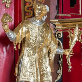 Zdjęcie nr 1: Rzeźba ścięta z tyłu i drążona, ustawiona na niskiej podstawie. Święty ukazany frontalnie, z głową skierowaną w prawo, w kontrapoście, o sylwetce lekko przechylonej w tył. W prawej, uniesionej ręce trzyma kamień, w lewej wysuniętej w bok liść palmy. Twarz ma szczupłą, kwadratową, o wyraźnie zarysowanej żuchwie, niewielkich, migdałowatych oczach, osadzonych blisko siebie, małym nosie i wąskich ustach. Włosy krótkie, silnie kręcone. Święty ubrany jest w albę, stułę skrzyżowaną na prawym boku, humerał, dalmatykę z płaskorzeźbionym wzorem kwiatowym i rocaille'em, na lewym przedramieniu ma manipularz. Figura niemal w całości złocona, alba i humerał srebrzone.