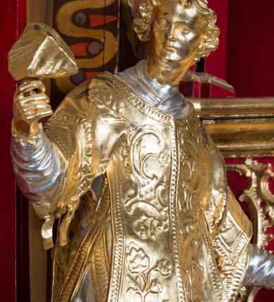 Zdjęcie nr 3: Rzeźba ścięta z tyłu i drążona, ustawiona na niskiej podstawie. Święty ukazany frontalnie, z głową skierowaną w prawo, w kontrapoście, o sylwetce lekko przechylonej w tył. W prawej, uniesionej ręce trzyma kamień, w lewej wysuniętej w bok liść palmy. Twarz ma szczupłą, kwadratową, o wyraźnie zarysowanej żuchwie, niewielkich, migdałowatych oczach, osadzonych blisko siebie, małym nosie i wąskich ustach. Włosy krótkie, silnie kręcone. Święty ubrany jest w albę, stułę skrzyżowaną na prawym boku, humerał, dalmatykę z płaskorzeźbionym wzorem kwiatowym i rocaille&#039;em, na lewym przedramieniu ma manipularz. Figura niemal w całości złocona, alba i humerał srebrzone.