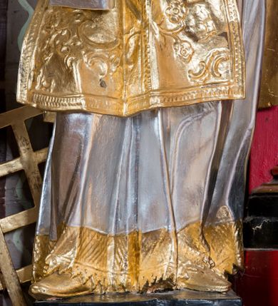 Zdjęcie nr 6: Rzeźba drążona, ustawiona na niskiej podstawie. Święty zwrócony w trzech czwartych w prawo, z uniesioną głową skierowaną w lewo, w kontrapoście, o esowato wygiętej sylwetce. W lewej ręce trzyma księgę opartą na prawym udzie, w prawej, wyciągniętej w bok trzyma ruszt. Twarz ma szczupłą, kwadratową, z wyraźnie zarysowaną żuchwą, niewielkimi, migdałowatymi oczami, osadzonymi blisko siebie, małym nosem i wąskimi ustami. Włosy krótkie, silnie kręcone. Święty ubrany jest w albę przewiązaną w talii, dalmatykę dekorowaną płaskorzeźbionym wzorem roślinnym, na lewym przedramieniu ma manipularz. Figura niemal w całości złocona, jedynie alba i księga są srebrzone.