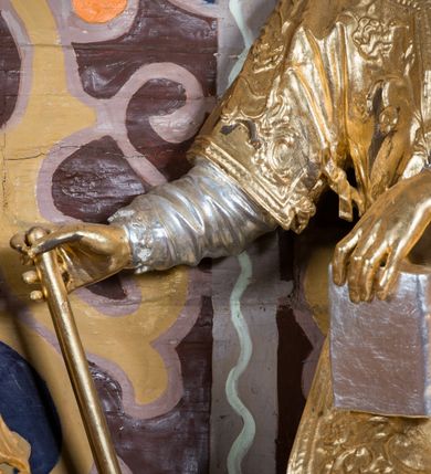 Zdjęcie nr 9: Rzeźba drążona, ustawiona na niskiej podstawie. Święty zwrócony w trzech czwartych w prawo, z uniesioną głową skierowaną w lewo, w kontrapoście, o esowato wygiętej sylwetce. W lewej ręce trzyma księgę opartą na prawym udzie, w prawej, wyciągniętej w bok trzyma ruszt. Twarz ma szczupłą, kwadratową, z wyraźnie zarysowaną żuchwą, niewielkimi, migdałowatymi oczami, osadzonymi blisko siebie, małym nosem i wąskimi ustami. Włosy krótkie, silnie kręcone. Święty ubrany jest w albę przewiązaną w talii, dalmatykę dekorowaną płaskorzeźbionym wzorem roślinnym, na lewym przedramieniu ma manipularz. Figura niemal w całości złocona, jedynie alba i księga są srebrzone.