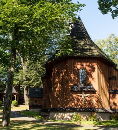 Zdjęcie nr 34: Kościół parafialny w Gruszowie znajduje się na niewielkim wzniesieniu w centrum miejscowości. Budowla jest orientowana, jednonawowa, z szerokim zamkniętym trójbocznie prezbiterium oraz czworoboczną wieżą od zachodu. Korpusu nawowy i prezbiterium charakteryzuje konstrukcja zrębowa, natomiast wieżę słupowa. Od północy do prezbiterium przylega zakrystia na rzucie prostokąta, natomiast do nawy zamknięta trójbocznie kaplica boczna. Do wnętrza kościoła prowadzą dwie kruchty, jedna od strony południowej, druga przez wieżę od zachodniej. Nad korpusem nawowym i prezbiterium znajduje się jednokalenicowy dach kryty gontem, a na styku nawy i prezbiterium usytuowana jest drewniana wieżyczka na sygnaturkę nakryta baniastym hełmem z latarnią. Zakrystia przekryta jest dachem pulpitowym, natomiast kaplica boczna oraz kruchty dachami dwuspadowymi krytymi gontem. Izbicową, o pochyłych ścianach wieżę wieńczy okuty blachą dach namiotowy. Elewacje osłania szalunek z pionowych desek z tzw. listwowaniem oraz pseudopilastry, dodatkowo wieżę w jednej trzeciej wysokości obiega niewielki parapet kryty gontem. W strukturze korpusu nawowego otwory okienne znajdują się po stronie południowej i mają kształt stojących prostokątów. W prezbiterium znajduje się po jednym oknie od południa i od wschodu, ich prostokątna forma jest zamknięta łukiem w ośli grzbiet. W kaplicy bocznej jest jedno okno od strony zachodniej. Ściana wschodnia zakrystii przepruta jest dwoma niewielkimi oknami, natomiast kruchty południowej jednym. W kruchcie zachodniej od południa jest jedno okno, natomiast w dolnej partii wieży znajdują się trzy, z czego dwa dolne oddziela od górnego niewielki daszek pulpitowy. Wnętrze korpusu nawowego i prezbiterium kościoła nakryte jest drewnianym stropem. Do kaplicy bocznej prowadzi szerokie przejście o ostrołukowym wykroju. Południowy portal w korpusie nawowym wieńczy wykrój w formie łuku w ośli grzbiet. Ściany i stropy wnętrza kościoła pokrywa secesyjna polichromia. 
Plac przykościelny otoczony jest drewnianym ogrodzeniem oraz starodrzewem.
