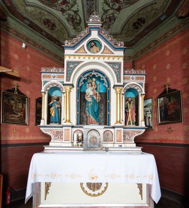 Zdjęcie nr 21: Kościół parafialny w Gruszowie znajduje się na niewielkim wzniesieniu w centrum miejscowości. Budowla jest orientowana, jednonawowa, z szerokim zamkniętym trójbocznie prezbiterium oraz czworoboczną wieżą od zachodu. Korpusu nawowy i prezbiterium charakteryzuje konstrukcja zrębowa, natomiast wieżę słupowa. Od północy do prezbiterium przylega zakrystia na rzucie prostokąta, natomiast do nawy zamknięta trójbocznie kaplica boczna. Do wnętrza kościoła prowadzą dwie kruchty, jedna od strony południowej, druga przez wieżę od zachodniej. Nad korpusem nawowym i prezbiterium znajduje się jednokalenicowy dach kryty gontem, a na styku nawy i prezbiterium usytuowana jest drewniana wieżyczka na sygnaturkę nakryta baniastym hełmem z latarnią. Zakrystia przekryta jest dachem pulpitowym, natomiast kaplica boczna oraz kruchty dachami dwuspadowymi krytymi gontem. Izbicową, o pochyłych ścianach wieżę wieńczy okuty blachą dach namiotowy. Elewacje osłania szalunek z pionowych desek z tzw. listwowaniem oraz pseudopilastry, dodatkowo wieżę w jednej trzeciej wysokości obiega niewielki parapet kryty gontem. W strukturze korpusu nawowego otwory okienne znajdują się po stronie południowej i mają kształt stojących prostokątów. W prezbiterium znajduje się po jednym oknie od południa i od wschodu, ich prostokątna forma jest zamknięta łukiem w ośli grzbiet. W kaplicy bocznej jest jedno okno od strony zachodniej. Ściana wschodnia zakrystii przepruta jest dwoma niewielkimi oknami, natomiast kruchty południowej jednym. W kruchcie zachodniej od południa jest jedno okno, natomiast w dolnej partii wieży znajdują się trzy, z czego dwa dolne oddziela od górnego niewielki daszek pulpitowy. Wnętrze korpusu nawowego i prezbiterium kościoła nakryte jest drewnianym stropem. Do kaplicy bocznej prowadzi szerokie przejście o ostrołukowym wykroju. Południowy portal w korpusie nawowym wieńczy wykrój w formie łuku w ośli grzbiet. Ściany i stropy wnętrza kościoła pokrywa secesyjna polichromia. 
Plac przykościelny otoczony jest drewnianym ogrodzeniem oraz starodrzewem.
