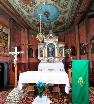 Zdjęcie nr 18: Kościół parafialny w Gruszowie znajduje się na niewielkim wzniesieniu w centrum miejscowości. Budowla jest orientowana, jednonawowa, z szerokim zamkniętym trójbocznie prezbiterium oraz czworoboczną wieżą od zachodu. Korpusu nawowy i prezbiterium charakteryzuje konstrukcja zrębowa, natomiast wieżę słupowa. Od północy do prezbiterium przylega zakrystia na rzucie prostokąta, natomiast do nawy zamknięta trójbocznie kaplica boczna. Do wnętrza kościoła prowadzą dwie kruchty, jedna od strony południowej, druga przez wieżę od zachodniej. Nad korpusem nawowym i prezbiterium znajduje się jednokalenicowy dach kryty gontem, a na styku nawy i prezbiterium usytuowana jest drewniana wieżyczka na sygnaturkę nakryta baniastym hełmem z latarnią. Zakrystia przekryta jest dachem pulpitowym, natomiast kaplica boczna oraz kruchty dachami dwuspadowymi krytymi gontem. Izbicową, o pochyłych ścianach wieżę wieńczy okuty blachą dach namiotowy. Elewacje osłania szalunek z pionowych desek z tzw. listwowaniem oraz pseudopilastry, dodatkowo wieżę w jednej trzeciej wysokości obiega niewielki parapet kryty gontem. W strukturze korpusu nawowego otwory okienne znajdują się po stronie południowej i mają kształt stojących prostokątów. W prezbiterium znajduje się po jednym oknie od południa i od wschodu, ich prostokątna forma jest zamknięta łukiem w ośli grzbiet. W kaplicy bocznej jest jedno okno od strony zachodniej. Ściana wschodnia zakrystii przepruta jest dwoma niewielkimi oknami, natomiast kruchty południowej jednym. W kruchcie zachodniej od południa jest jedno okno, natomiast w dolnej partii wieży znajdują się trzy, z czego dwa dolne oddziela od górnego niewielki daszek pulpitowy. Wnętrze korpusu nawowego i prezbiterium kościoła nakryte jest drewnianym stropem. Do kaplicy bocznej prowadzi szerokie przejście o ostrołukowym wykroju. Południowy portal w korpusie nawowym wieńczy wykrój w formie łuku w ośli grzbiet. Ściany i stropy wnętrza kościoła pokrywa secesyjna polichromia. 
Plac przykościelny otoczony jest drewnianym ogrodzeniem oraz starodrzewem.
