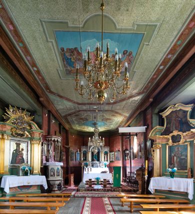 Zdjęcie nr 11: Kościół parafialny w Gruszowie znajduje się na niewielkim wzniesieniu w centrum miejscowości. Budowla jest orientowana, jednonawowa, z szerokim zamkniętym trójbocznie prezbiterium oraz czworoboczną wieżą od zachodu. Korpusu nawowy i prezbiterium charakteryzuje konstrukcja zrębowa, natomiast wieżę słupowa. Od północy do prezbiterium przylega zakrystia na rzucie prostokąta, natomiast do nawy zamknięta trójbocznie kaplica boczna. Do wnętrza kościoła prowadzą dwie kruchty, jedna od strony południowej, druga przez wieżę od zachodniej. Nad korpusem nawowym i prezbiterium znajduje się jednokalenicowy dach kryty gontem, a na styku nawy i prezbiterium usytuowana jest drewniana wieżyczka na sygnaturkę nakryta baniastym hełmem z latarnią. Zakrystia przekryta jest dachem pulpitowym, natomiast kaplica boczna oraz kruchty dachami dwuspadowymi krytymi gontem. Izbicową, o pochyłych ścianach wieżę wieńczy okuty blachą dach namiotowy. Elewacje osłania szalunek z pionowych desek z tzw. listwowaniem oraz pseudopilastry, dodatkowo wieżę w jednej trzeciej wysokości obiega niewielki parapet kryty gontem. W strukturze korpusu nawowego otwory okienne znajdują się po stronie południowej i mają kształt stojących prostokątów. W prezbiterium znajduje się po jednym oknie od południa i od wschodu, ich prostokątna forma jest zamknięta łukiem w ośli grzbiet. W kaplicy bocznej jest jedno okno od strony zachodniej. Ściana wschodnia zakrystii przepruta jest dwoma niewielkimi oknami, natomiast kruchty południowej jednym. W kruchcie zachodniej od południa jest jedno okno, natomiast w dolnej partii wieży znajdują się trzy, z czego dwa dolne oddziela od górnego niewielki daszek pulpitowy. Wnętrze korpusu nawowego i prezbiterium kościoła nakryte jest drewnianym stropem. Do kaplicy bocznej prowadzi szerokie przejście o ostrołukowym wykroju. Południowy portal w korpusie nawowym wieńczy wykrój w formie łuku w ośli grzbiet. Ściany i stropy wnętrza kościoła pokrywa secesyjna polichromia. 
Plac przykościelny otoczony jest drewnianym ogrodzeniem oraz starodrzewem.
