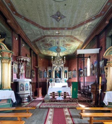 Zdjęcie nr 14: Kościół parafialny w Gruszowie znajduje się na niewielkim wzniesieniu w centrum miejscowości. Budowla jest orientowana, jednonawowa, z szerokim zamkniętym trójbocznie prezbiterium oraz czworoboczną wieżą od zachodu. Korpusu nawowy i prezbiterium charakteryzuje konstrukcja zrębowa, natomiast wieżę słupowa. Od północy do prezbiterium przylega zakrystia na rzucie prostokąta, natomiast do nawy zamknięta trójbocznie kaplica boczna. Do wnętrza kościoła prowadzą dwie kruchty, jedna od strony południowej, druga przez wieżę od zachodniej. Nad korpusem nawowym i prezbiterium znajduje się jednokalenicowy dach kryty gontem, a na styku nawy i prezbiterium usytuowana jest drewniana wieżyczka na sygnaturkę nakryta baniastym hełmem z latarnią. Zakrystia przekryta jest dachem pulpitowym, natomiast kaplica boczna oraz kruchty dachami dwuspadowymi krytymi gontem. Izbicową, o pochyłych ścianach wieżę wieńczy okuty blachą dach namiotowy. Elewacje osłania szalunek z pionowych desek z tzw. listwowaniem oraz pseudopilastry, dodatkowo wieżę w jednej trzeciej wysokości obiega niewielki parapet kryty gontem. W strukturze korpusu nawowego otwory okienne znajdują się po stronie południowej i mają kształt stojących prostokątów. W prezbiterium znajduje się po jednym oknie od południa i od wschodu, ich prostokątna forma jest zamknięta łukiem w ośli grzbiet. W kaplicy bocznej jest jedno okno od strony zachodniej. Ściana wschodnia zakrystii przepruta jest dwoma niewielkimi oknami, natomiast kruchty południowej jednym. W kruchcie zachodniej od południa jest jedno okno, natomiast w dolnej partii wieży znajdują się trzy, z czego dwa dolne oddziela od górnego niewielki daszek pulpitowy. Wnętrze korpusu nawowego i prezbiterium kościoła nakryte jest drewnianym stropem. Do kaplicy bocznej prowadzi szerokie przejście o ostrołukowym wykroju. Południowy portal w korpusie nawowym wieńczy wykrój w formie łuku w ośli grzbiet. Ściany i stropy wnętrza kościoła pokrywa secesyjna polichromia. 
Plac przykościelny otoczony jest drewnianym ogrodzeniem oraz starodrzewem.
