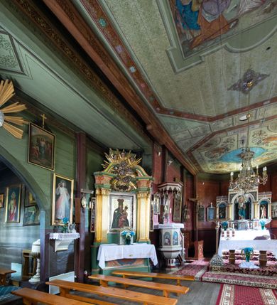 Zdjęcie nr 17: Kościół parafialny w Gruszowie znajduje się na niewielkim wzniesieniu w centrum miejscowości. Budowla jest orientowana, jednonawowa, z szerokim zamkniętym trójbocznie prezbiterium oraz czworoboczną wieżą od zachodu. Korpusu nawowy i prezbiterium charakteryzuje konstrukcja zrębowa, natomiast wieżę słupowa. Od północy do prezbiterium przylega zakrystia na rzucie prostokąta, natomiast do nawy zamknięta trójbocznie kaplica boczna. Do wnętrza kościoła prowadzą dwie kruchty, jedna od strony południowej, druga przez wieżę od zachodniej. Nad korpusem nawowym i prezbiterium znajduje się jednokalenicowy dach kryty gontem, a na styku nawy i prezbiterium usytuowana jest drewniana wieżyczka na sygnaturkę nakryta baniastym hełmem z latarnią. Zakrystia przekryta jest dachem pulpitowym, natomiast kaplica boczna oraz kruchty dachami dwuspadowymi krytymi gontem. Izbicową, o pochyłych ścianach wieżę wieńczy okuty blachą dach namiotowy. Elewacje osłania szalunek z pionowych desek z tzw. listwowaniem oraz pseudopilastry, dodatkowo wieżę w jednej trzeciej wysokości obiega niewielki parapet kryty gontem. W strukturze korpusu nawowego otwory okienne znajdują się po stronie południowej i mają kształt stojących prostokątów. W prezbiterium znajduje się po jednym oknie od południa i od wschodu, ich prostokątna forma jest zamknięta łukiem w ośli grzbiet. W kaplicy bocznej jest jedno okno od strony zachodniej. Ściana wschodnia zakrystii przepruta jest dwoma niewielkimi oknami, natomiast kruchty południowej jednym. W kruchcie zachodniej od południa jest jedno okno, natomiast w dolnej partii wieży znajdują się trzy, z czego dwa dolne oddziela od górnego niewielki daszek pulpitowy. Wnętrze korpusu nawowego i prezbiterium kościoła nakryte jest drewnianym stropem. Do kaplicy bocznej prowadzi szerokie przejście o ostrołukowym wykroju. Południowy portal w korpusie nawowym wieńczy wykrój w formie łuku w ośli grzbiet. Ściany i stropy wnętrza kościoła pokrywa secesyjna polichromia. 
Plac przykościelny otoczony jest drewnianym ogrodzeniem oraz starodrzewem.
