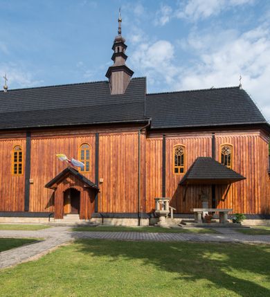 Zdjęcie nr 17: Kościół drewniany o konstrukcji zrębowej, elewacje jednolite, szalowane pionowo z listwowaniem, kruchta zachodnia o konstrukcji słupowo-ramowej. Więźba dachowa drewniana, krokwiowa. Budynek na kamiennym podmurowaniu przesłoniętym daszkiem gontowym. Kościół orientowany, jednonawowy, nawa na rzucie prostokąta, prezbiterium węższe, zakończone trójbocznie. Do wschodniej ściany prezbiterium przylega Ogrójec na rzucie prostokąta, od północy piętrowa zakrystia na planie prostokąta. Do południowej ściany nawy przylega niewielka kruchta na rzucie prostokąta oraz ołtarz polowy, od zachodu kruchta na planie prostokąta z węższym pięterkiem dzwonnym. Wnętrze podzielone lizenami, nakryte pułapami deskowymi. Pomiędzy nawą a prezbiterium prostokątny otwór tęczowy o zaokrąglonych narożach. Parapet chóru muzycznego w zachodniej części nawy podparty przez dwie kolumny o stylizowanych kapitelach. Otwory drzwiowe o prostokątnym wykroju w północnej ścianie prezbiterium, południowej i zachodniej nawy. Posadzka z płyt ceramicznych. Elewacja frontowa jednoosiowa. Na osi wejście do kruchty z dwuskrzydłowymi drzwiami, nakryte osobnym daszkiem dwuspadowym. Na północnej i południowej ścianie kruchty i pięterka dzwonnego niewielkie okna. Kruchta nakryta daszkiem trójspadowym gontowym, dzwonnica dwuspadowym, z krzyżem w partii szczytu. W elewacji południowej cztery otwory okienne w formie stojącego prostokąta zamkniętego łukiem półkolistym i odcinkowym, dwa w nawie i dwa w prezbiterium, w elewacji północnej dwa analogiczne otwory okienne. Na ścianie północnej zachowany fragment dawnych sobót, zabudowany pionowymi deskami. Na ścianie wschodniej prezbiterium Ogrójec w formie kapliczki przesłoniętej daszkiem dwuspadowym. Nawa nakryta dachem gontowym, dwuspadowym, półszczytowym, prezbiterium osobnym dachem wielospadowym, zakrystia przesłonięta dachem przyczółkowym, kruchta dwuspadowym, a ołtarz polowy trójspadowym. Nad nawą od strony prezbiterium wznosi się sześcioboczna wieżyczka na sygnaturkę z latarnią i hełmem cebulastym z kulą i krzyżem pokryta blachą. 



 
 
