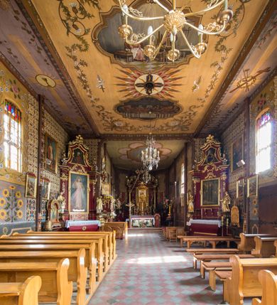 Zdjęcie nr 20: Kościół drewniany o konstrukcji zrębowej, elewacje jednolite, szalowane pionowo z listwowaniem, kruchta zachodnia o konstrukcji słupowo-ramowej. Więźba dachowa drewniana, krokwiowa. Budynek na kamiennym podmurowaniu przesłoniętym daszkiem gontowym. Kościół orientowany, jednonawowy, nawa na rzucie prostokąta, prezbiterium węższe, zakończone trójbocznie. Do wschodniej ściany prezbiterium przylega Ogrójec na rzucie prostokąta, od północy piętrowa zakrystia na planie prostokąta. Do południowej ściany nawy przylega niewielka kruchta na rzucie prostokąta oraz ołtarz polowy, od zachodu kruchta na planie prostokąta z węższym pięterkiem dzwonnym. Wnętrze podzielone lizenami, nakryte pułapami deskowymi. Pomiędzy nawą a prezbiterium prostokątny otwór tęczowy o zaokrąglonych narożach. Parapet chóru muzycznego w zachodniej części nawy podparty przez dwie kolumny o stylizowanych kapitelach. Otwory drzwiowe o prostokątnym wykroju w północnej ścianie prezbiterium, południowej i zachodniej nawy. Posadzka z płyt ceramicznych. Elewacja frontowa jednoosiowa. Na osi wejście do kruchty z dwuskrzydłowymi drzwiami, nakryte osobnym daszkiem dwuspadowym. Na północnej i południowej ścianie kruchty i pięterka dzwonnego niewielkie okna. Kruchta nakryta daszkiem trójspadowym gontowym, dzwonnica dwuspadowym, z krzyżem w partii szczytu. W elewacji południowej cztery otwory okienne w formie stojącego prostokąta zamkniętego łukiem półkolistym i odcinkowym, dwa w nawie i dwa w prezbiterium, w elewacji północnej dwa analogiczne otwory okienne. Na ścianie północnej zachowany fragment dawnych sobót, zabudowany pionowymi deskami. Na ścianie wschodniej prezbiterium Ogrójec w formie kapliczki przesłoniętej daszkiem dwuspadowym. Nawa nakryta dachem gontowym, dwuspadowym, półszczytowym, prezbiterium osobnym dachem wielospadowym, zakrystia przesłonięta dachem przyczółkowym, kruchta dwuspadowym, a ołtarz polowy trójspadowym. Nad nawą od strony prezbiterium wznosi się sześcioboczna wieżyczka na sygnaturkę z latarnią i hełmem cebulastym z kulą i krzyżem pokryta blachą. 



 
 
