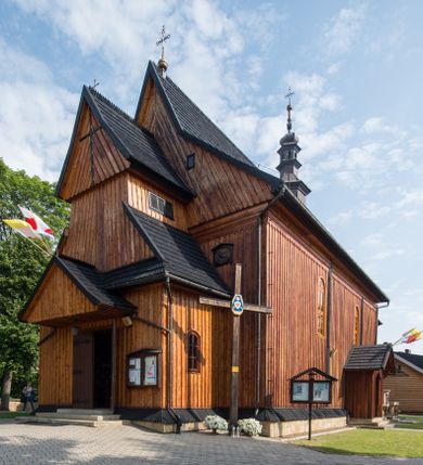 Zdjęcie nr 1: Kościół drewniany o konstrukcji zrębowej, elewacje jednolite, szalowane pionowo z listwowaniem, kruchta zachodnia o konstrukcji słupowo-ramowej. Więźba dachowa drewniana, krokwiowa. Budynek na kamiennym podmurowaniu przesłoniętym daszkiem gontowym. Kościół orientowany, jednonawowy, nawa na rzucie prostokąta, prezbiterium węższe, zakończone trójbocznie. Do wschodniej ściany prezbiterium przylega Ogrójec na rzucie prostokąta, od północy piętrowa zakrystia na planie prostokąta. Do południowej ściany nawy przylega niewielka kruchta na rzucie prostokąta oraz ołtarz polowy, od zachodu kruchta na planie prostokąta z węższym pięterkiem dzwonnym. Wnętrze podzielone lizenami, nakryte pułapami deskowymi. Pomiędzy nawą a prezbiterium prostokątny otwór tęczowy o zaokrąglonych narożach. Parapet chóru muzycznego w zachodniej części nawy podparty przez dwie kolumny o stylizowanych kapitelach. Otwory drzwiowe o prostokątnym wykroju w północnej ścianie prezbiterium, południowej i zachodniej nawy. Posadzka z płyt ceramicznych. Elewacja frontowa jednoosiowa. Na osi wejście do kruchty z dwuskrzydłowymi drzwiami, nakryte osobnym daszkiem dwuspadowym. Na północnej i południowej ścianie kruchty i pięterka dzwonnego niewielkie okna. Kruchta nakryta daszkiem trójspadowym gontowym, dzwonnica dwuspadowym, z krzyżem w partii szczytu. W elewacji południowej cztery otwory okienne w formie stojącego prostokąta zamkniętego łukiem półkolistym i odcinkowym, dwa w nawie i dwa w prezbiterium, w elewacji północnej dwa analogiczne otwory okienne. Na ścianie północnej zachowany fragment dawnych sobót, zabudowany pionowymi deskami. Na ścianie wschodniej prezbiterium Ogrójec w formie kapliczki przesłoniętej daszkiem dwuspadowym. Nawa nakryta dachem gontowym, dwuspadowym, półszczytowym, prezbiterium osobnym dachem wielospadowym, zakrystia przesłonięta dachem przyczółkowym, kruchta dwuspadowym, a ołtarz polowy trójspadowym. Nad nawą od strony prezbiterium wznosi się sześcioboczna wieżyczka na sygnaturkę z latarnią i hełmem cebulastym z kulą i krzyżem pokryta blachą. 



 
 
