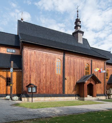 Zdjęcie nr 15: Kościół drewniany o konstrukcji zrębowej, elewacje jednolite, szalowane pionowo z listwowaniem, kruchta zachodnia o konstrukcji słupowo-ramowej. Więźba dachowa drewniana, krokwiowa. Budynek na kamiennym podmurowaniu przesłoniętym daszkiem gontowym. Kościół orientowany, jednonawowy, nawa na rzucie prostokąta, prezbiterium węższe, zakończone trójbocznie. Do wschodniej ściany prezbiterium przylega Ogrójec na rzucie prostokąta, od północy piętrowa zakrystia na planie prostokąta. Do południowej ściany nawy przylega niewielka kruchta na rzucie prostokąta oraz ołtarz polowy, od zachodu kruchta na planie prostokąta z węższym pięterkiem dzwonnym. Wnętrze podzielone lizenami, nakryte pułapami deskowymi. Pomiędzy nawą a prezbiterium prostokątny otwór tęczowy o zaokrąglonych narożach. Parapet chóru muzycznego w zachodniej części nawy podparty przez dwie kolumny o stylizowanych kapitelach. Otwory drzwiowe o prostokątnym wykroju w północnej ścianie prezbiterium, południowej i zachodniej nawy. Posadzka z płyt ceramicznych. Elewacja frontowa jednoosiowa. Na osi wejście do kruchty z dwuskrzydłowymi drzwiami, nakryte osobnym daszkiem dwuspadowym. Na północnej i południowej ścianie kruchty i pięterka dzwonnego niewielkie okna. Kruchta nakryta daszkiem trójspadowym gontowym, dzwonnica dwuspadowym, z krzyżem w partii szczytu. W elewacji południowej cztery otwory okienne w formie stojącego prostokąta zamkniętego łukiem półkolistym i odcinkowym, dwa w nawie i dwa w prezbiterium, w elewacji północnej dwa analogiczne otwory okienne. Na ścianie północnej zachowany fragment dawnych sobót, zabudowany pionowymi deskami. Na ścianie wschodniej prezbiterium Ogrójec w formie kapliczki przesłoniętej daszkiem dwuspadowym. Nawa nakryta dachem gontowym, dwuspadowym, półszczytowym, prezbiterium osobnym dachem wielospadowym, zakrystia przesłonięta dachem przyczółkowym, kruchta dwuspadowym, a ołtarz polowy trójspadowym. Nad nawą od strony prezbiterium wznosi się sześcioboczna wieżyczka na sygnaturkę z latarnią i hełmem cebulastym z kulą i krzyżem pokryta blachą. 



 
 
