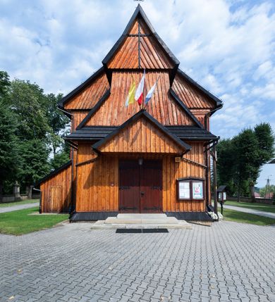 Zdjęcie nr 3: Kościół drewniany o konstrukcji zrębowej, elewacje jednolite, szalowane pionowo z listwowaniem, kruchta zachodnia o konstrukcji słupowo-ramowej. Więźba dachowa drewniana, krokwiowa. Budynek na kamiennym podmurowaniu przesłoniętym daszkiem gontowym. Kościół orientowany, jednonawowy, nawa na rzucie prostokąta, prezbiterium węższe, zakończone trójbocznie. Do wschodniej ściany prezbiterium przylega Ogrójec na rzucie prostokąta, od północy piętrowa zakrystia na planie prostokąta. Do południowej ściany nawy przylega niewielka kruchta na rzucie prostokąta oraz ołtarz polowy, od zachodu kruchta na planie prostokąta z węższym pięterkiem dzwonnym. Wnętrze podzielone lizenami, nakryte pułapami deskowymi. Pomiędzy nawą a prezbiterium prostokątny otwór tęczowy o zaokrąglonych narożach. Parapet chóru muzycznego w zachodniej części nawy podparty przez dwie kolumny o stylizowanych kapitelach. Otwory drzwiowe o prostokątnym wykroju w północnej ścianie prezbiterium, południowej i zachodniej nawy. Posadzka z płyt ceramicznych. Elewacja frontowa jednoosiowa. Na osi wejście do kruchty z dwuskrzydłowymi drzwiami, nakryte osobnym daszkiem dwuspadowym. Na północnej i południowej ścianie kruchty i pięterka dzwonnego niewielkie okna. Kruchta nakryta daszkiem trójspadowym gontowym, dzwonnica dwuspadowym, z krzyżem w partii szczytu. W elewacji południowej cztery otwory okienne w formie stojącego prostokąta zamkniętego łukiem półkolistym i odcinkowym, dwa w nawie i dwa w prezbiterium, w elewacji północnej dwa analogiczne otwory okienne. Na ścianie północnej zachowany fragment dawnych sobót, zabudowany pionowymi deskami. Na ścianie wschodniej prezbiterium Ogrójec w formie kapliczki przesłoniętej daszkiem dwuspadowym. Nawa nakryta dachem gontowym, dwuspadowym, półszczytowym, prezbiterium osobnym dachem wielospadowym, zakrystia przesłonięta dachem przyczółkowym, kruchta dwuspadowym, a ołtarz polowy trójspadowym. Nad nawą od strony prezbiterium wznosi się sześcioboczna wieżyczka na sygnaturkę z latarnią i hełmem cebulastym z kulą i krzyżem pokryta blachą. 



 
 
