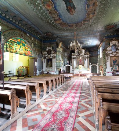 Zdjęcie nr 3: Kościół pw. św. Wawrzyńca w Grojcu jest drewnianą budowlą orientowaną, jednonawową z trójbocznie zamkniętym węższym prezbiterium od wschodu i wieżą od zachodu. Prostokątna nawa została wzniesiona na zrąb. Nawę i prezbiterium przykrywa dach siodłowy pokryty blachą cynkowaną. Do prezbiterium od północy przylega murowana zakrystia na rzucie prostokąta nakryta blaszanym dachem pulpitowym, a od południa prostokątny, drewniany aneks pełniący funkcję kaplicy bocznej, o podobnym dachu. Od północy do nawy dostawiono murowaną kaplicę na rzucie prostokąta przylegającą do zakrystii, a od południa niewielką czworoboczną kruchtę. Obie przestrzenie przykryto blaszanym dachem pulpitowym. W kruchcie południowej znajduje się drewniany portal z nadprożem w wykroju w ośli grzbiet. Nad wschodnią częścią nawy usytuowano sygnaturkę w kształcie wielobocznej latarni z krzyżem. Od zachodu do nawy dostawiono czworoboczną, drewnianą wieżę wzniesioną w konstrukcji słupowej, która w połowie nad nawą jest nadwieszona. Jej ściany są pionowe podzielone daszkami na trzy kondygnacje. Nakrywa ją blaszany, namiotowy hełm z latarnią zwieńczoną krzyżem. W przyziemiu wieży urządzono kruchtę. Wnętrze kościoła nakryto stropem z fasetą oddzieloną od ścian gzymsem. W zachodniej części nawy urządzono chór muzyczny zawieszony na dwóch kroksztynach i wsparty na kolumnach. W prezbiterium na ścianie wschodniej znajduje się ołtarz główny, a w nawie przy tęczy dwa ołtarze boczne oraz ambona.   