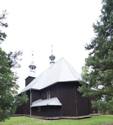 Zdjęcie nr 16: Kościół pw. św. Wawrzyńca w Grojcu jest drewnianą budowlą orientowaną, jednonawową z trójbocznie zamkniętym węższym prezbiterium od wschodu i wieżą od zachodu. Prostokątna nawa została wzniesiona na zrąb. Nawę i prezbiterium przykrywa dach siodłowy pokryty blachą cynkowaną. Do prezbiterium od północy przylega murowana zakrystia na rzucie prostokąta nakryta blaszanym dachem pulpitowym, a od południa prostokątny, drewniany aneks pełniący funkcję kaplicy bocznej, o podobnym dachu. Od północy do nawy dostawiono murowaną kaplicę na rzucie prostokąta przylegającą do zakrystii, a od południa niewielką czworoboczną kruchtę. Obie przestrzenie przykryto blaszanym dachem pulpitowym. W kruchcie południowej znajduje się drewniany portal z nadprożem w wykroju w ośli grzbiet. Nad wschodnią częścią nawy usytuowano sygnaturkę w kształcie wielobocznej latarni z krzyżem. Od zachodu do nawy dostawiono czworoboczną, drewnianą wieżę wzniesioną w konstrukcji słupowej, która w połowie nad nawą jest nadwieszona. Jej ściany są pionowe podzielone daszkami na trzy kondygnacje. Nakrywa ją blaszany, namiotowy hełm z latarnią zwieńczoną krzyżem. W przyziemiu wieży urządzono kruchtę. Wnętrze kościoła nakryto stropem z fasetą oddzieloną od ścian gzymsem. W zachodniej części nawy urządzono chór muzyczny zawieszony na dwóch kroksztynach i wsparty na kolumnach. W prezbiterium na ścianie wschodniej znajduje się ołtarz główny, a w nawie przy tęczy dwa ołtarze boczne oraz ambona.   