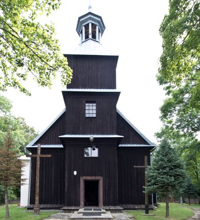 Zdjęcie nr 1: Kościół pw. św. Wawrzyńca w Grojcu jest drewnianą budowlą orientowaną, jednonawową z trójbocznie zamkniętym węższym prezbiterium od wschodu i wieżą od zachodu. Prostokątna nawa została wzniesiona na zrąb. Nawę i prezbiterium przykrywa dach siodłowy pokryty blachą cynkowaną. Do prezbiterium od północy przylega murowana zakrystia na rzucie prostokąta nakryta blaszanym dachem pulpitowym, a od południa prostokątny, drewniany aneks pełniący funkcję kaplicy bocznej, o podobnym dachu. Od północy do nawy dostawiono murowaną kaplicę na rzucie prostokąta przylegającą do zakrystii, a od południa niewielką czworoboczną kruchtę. Obie przestrzenie przykryto blaszanym dachem pulpitowym. W kruchcie południowej znajduje się drewniany portal z nadprożem w wykroju w ośli grzbiet. Nad wschodnią częścią nawy usytuowano sygnaturkę w kształcie wielobocznej latarni z krzyżem. Od zachodu do nawy dostawiono czworoboczną, drewnianą wieżę wzniesioną w konstrukcji słupowej, która w połowie nad nawą jest nadwieszona. Jej ściany są pionowe podzielone daszkami na trzy kondygnacje. Nakrywa ją blaszany, namiotowy hełm z latarnią zwieńczoną krzyżem. W przyziemiu wieży urządzono kruchtę. Wnętrze kościoła nakryto stropem z fasetą oddzieloną od ścian gzymsem. W zachodniej części nawy urządzono chór muzyczny zawieszony na dwóch kroksztynach i wsparty na kolumnach. W prezbiterium na ścianie wschodniej znajduje się ołtarz główny, a w nawie przy tęczy dwa ołtarze boczne oraz ambona.   