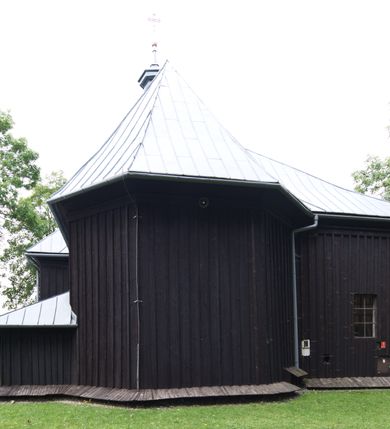 Zdjęcie nr 15: Kościół pw. św. Wawrzyńca w Grojcu jest drewnianą budowlą orientowaną, jednonawową z trójbocznie zamkniętym węższym prezbiterium od wschodu i wieżą od zachodu. Prostokątna nawa została wzniesiona na zrąb. Nawę i prezbiterium przykrywa dach siodłowy pokryty blachą cynkowaną. Do prezbiterium od północy przylega murowana zakrystia na rzucie prostokąta nakryta blaszanym dachem pulpitowym, a od południa prostokątny, drewniany aneks pełniący funkcję kaplicy bocznej, o podobnym dachu. Od północy do nawy dostawiono murowaną kaplicę na rzucie prostokąta przylegającą do zakrystii, a od południa niewielką czworoboczną kruchtę. Obie przestrzenie przykryto blaszanym dachem pulpitowym. W kruchcie południowej znajduje się drewniany portal z nadprożem w wykroju w ośli grzbiet. Nad wschodnią częścią nawy usytuowano sygnaturkę w kształcie wielobocznej latarni z krzyżem. Od zachodu do nawy dostawiono czworoboczną, drewnianą wieżę wzniesioną w konstrukcji słupowej, która w połowie nad nawą jest nadwieszona. Jej ściany są pionowe podzielone daszkami na trzy kondygnacje. Nakrywa ją blaszany, namiotowy hełm z latarnią zwieńczoną krzyżem. W przyziemiu wieży urządzono kruchtę. Wnętrze kościoła nakryto stropem z fasetą oddzieloną od ścian gzymsem. W zachodniej części nawy urządzono chór muzyczny zawieszony na dwóch kroksztynach i wsparty na kolumnach. W prezbiterium na ścianie wschodniej znajduje się ołtarz główny, a w nawie przy tęczy dwa ołtarze boczne oraz ambona.   