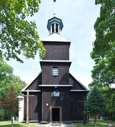 Zdjęcie nr 2: Kościół pw. św. Wawrzyńca w Grojcu jest drewnianą budowlą orientowaną, jednonawową z trójbocznie zamkniętym węższym prezbiterium od wschodu i wieżą od zachodu. Prostokątna nawa została wzniesiona na zrąb. Nawę i prezbiterium przykrywa dach siodłowy pokryty blachą cynkowaną. Do prezbiterium od północy przylega murowana zakrystia na rzucie prostokąta nakryta blaszanym dachem pulpitowym, a od południa prostokątny, drewniany aneks pełniący funkcję kaplicy bocznej, o podobnym dachu. Od północy do nawy dostawiono murowaną kaplicę na rzucie prostokąta przylegającą do zakrystii, a od południa niewielką czworoboczną kruchtę. Obie przestrzenie przykryto blaszanym dachem pulpitowym. W kruchcie południowej znajduje się drewniany portal z nadprożem w wykroju w ośli grzbiet. Nad wschodnią częścią nawy usytuowano sygnaturkę w kształcie wielobocznej latarni z krzyżem. Od zachodu do nawy dostawiono czworoboczną, drewnianą wieżę wzniesioną w konstrukcji słupowej, która w połowie nad nawą jest nadwieszona. Jej ściany są pionowe podzielone daszkami na trzy kondygnacje. Nakrywa ją blaszany, namiotowy hełm z latarnią zwieńczoną krzyżem. W przyziemiu wieży urządzono kruchtę. Wnętrze kościoła nakryto stropem z fasetą oddzieloną od ścian gzymsem. W zachodniej części nawy urządzono chór muzyczny zawieszony na dwóch kroksztynach i wsparty na kolumnach. W prezbiterium na ścianie wschodniej znajduje się ołtarz główny, a w nawie przy tęczy dwa ołtarze boczne oraz ambona.   