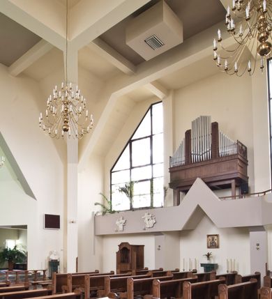 Zdjęcie nr 4: Orientowany kościół w Grojcu został wzniesiony jako świątynia salowa na rzucie wydłużonego prostokąta z nieznacznie wysuniętym poza zarys nawy transeptem. Nawę od wschodu kończy trójbocznie zamknięte prezbiterium, wpisane w obrys usytuowanej od wschodu prostokątnej zakrystii. Natomiast od zachodu zamyka ją nieznacznie wysunięta do przodu czworoboczna wieża, w przyziemiu której urządzono kruchtę. Wieżę wieńczy ostrosłupowy hełm z krzyżem wsparty na trójbocznych przyczółkach zamykających u góry płaszczyzny ścian bocznych. Poniżej hełmu widocznie są trójkątnie zamknięte, prostokątne okna, a pod nimi na ścianie zachodniej zainstalowany zegar. Po bokach wieży ściany nawy zostały przeprute monumentalnymi, trapezoidalnymi oknami doświetlającymi chór muzyczny i wnętrze świątyni. Podobne okna wprowadzono w ścianie południowej i północnej transeptu. Wnętrze kościoła nakryto żelbetonowym, płaskim stropem wspartym na łamanych filarach, stanowiących stylizowaną wersję sklepienia lustrzanego. W części zachodniej nawy oraz w ramionach transeptu wprowadzono połączone ze sobą empory. Na emporze zachodniej urządzono chór muzyczny ze współczesnym prospektem organowym. Prezbiterium zostało podniesione o kilka stopni w stosunku do poziomu posadzki nawy.  Ustawiono w nim marmurowy ołtarz posoborowy oraz ambonkę, dekorując środkową ścianę prezbiterium monumentalną, rzeźbioną postacią Chrystusa Zmartwychwstałego. Na ścianie północnej zawieszono w dekoracyjnej, romboidalnej ramie wizerunek Matki Boskiej Ostrobramskiej. 