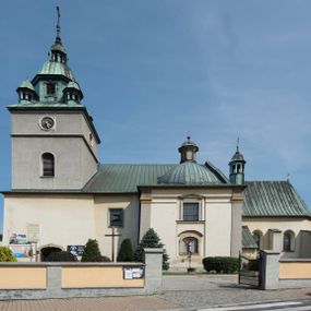 Zdjęcie nr 1: Kościół orientowany, jest budowlą murowaną z cegły i kamienia, na rzucie podłużnym. Korpus trójnawowy i dwuprzęsłowy. Prezbiterium trójprzęsłowe, zamknięte trójbocznie prezbiterium z przylegającymi od północy zakrystią, od południa kruchtą. Na osi kościoła, jednokondygnacyjna, szeroka, przysadzista wieża z kruchtą w przyziemiu i przyległością od zachodu.  Od południa i zachodu, w obrębie pierwszego przęsła naw bocznych jest para kaplic na rzutach zbliżonych do kwadratu. Nawa i prezbiterium przekryte są sklepieniami kolebkowymi z lunetami wspartymi na pilastrach i filarach. Kaplice wieńczą kopuły. Artykulację ścian na zewnątrz prezbiterium stanowi zespół przypór, naroża kaplic ujmują pilastry wpierające obiegający bryłę niepełne belkowanie.
Do wnętrza prowadzi 6 otworów drzwiowych, z czego 2 w kruchcie w wieży ujęte kamiennymi portalami zamkniętymi łukiem koszowym i do kaplicy ujętym kamiennym portalem w formie pary lizen na wysokich cokołach wspierających belkowanie z parą rozet w partii fryzu. Okna korpusu nawowego w kształcie stojących prostokątów, prezbiterium ostrołukowe, natomiast kaplic są prostokątne ujęte kamiennym obramieniem z uszakami w górnych narożach i zwieńczone trójkątnymi przyczółkami. Wieża artykułowana w 2/3 wysokości gzymsem. W dolnej strefie w 3 z 4 ścian po jednym, zamkniętym półkoliście oknie. W górnej partii pośrodku  z czterech po 1 okrągłej tarczy zegara. Wieże wieńczy hełm ujęty 4 latarniami i zwieńczony piątą. Dachy korpusu i prezbiterium dwuspadowe, nad kaplicami kopuły z latarniami, nad zakrystią i kruchtą boczną pulpitowe. Tynki ścian w odcieniach bieli i szarości. 
