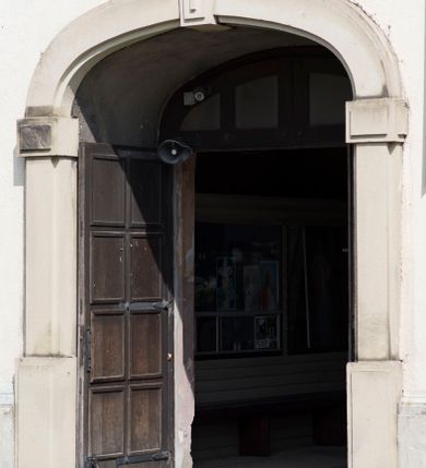 Zdjęcie nr 24: Kościół orientowany, jest budowlą murowaną z cegły i kamienia, na rzucie podłużnym. Korpus trójnawowy i dwuprzęsłowy. Prezbiterium trójprzęsłowe, zamknięte trójbocznie prezbiterium z przylegającymi od północy zakrystią, od południa kruchtą. Na osi kościoła, jednokondygnacyjna, szeroka, przysadzista wieża z kruchtą w przyziemiu i przyległością od zachodu.  Od południa i zachodu, w obrębie pierwszego przęsła naw bocznych jest para kaplic na rzutach zbliżonych do kwadratu. Nawa i prezbiterium przekryte są sklepieniami kolebkowymi z lunetami wspartymi na pilastrach i filarach. Kaplice wieńczą kopuły. Artykulację ścian na zewnątrz prezbiterium stanowi zespół przypór, naroża kaplic ujmują pilastry wpierające obiegający bryłę niepełne belkowanie.
Do wnętrza prowadzi 6 otworów drzwiowych, z czego 2 w kruchcie w wieży ujęte kamiennymi portalami zamkniętymi łukiem koszowym i do kaplicy ujętym kamiennym portalem w formie pary lizen na wysokich cokołach wspierających belkowanie z parą rozet w partii fryzu. Okna korpusu nawowego w kształcie stojących prostokątów, prezbiterium ostrołukowe, natomiast kaplic są prostokątne ujęte kamiennym obramieniem z uszakami w górnych narożach i zwieńczone trójkątnymi przyczółkami. Wieża artykułowana w 2/3 wysokości gzymsem. W dolnej strefie w 3 z 4 ścian po jednym, zamkniętym półkoliście oknie. W górnej partii pośrodku  z czterech po 1 okrągłej tarczy zegara. Wieże wieńczy hełm ujęty 4 latarniami i zwieńczony piątą. Dachy korpusu i prezbiterium dwuspadowe, nad kaplicami kopuły z latarniami, nad zakrystią i kruchtą boczną pulpitowe. Tynki ścian w odcieniach bieli i szarości. 
